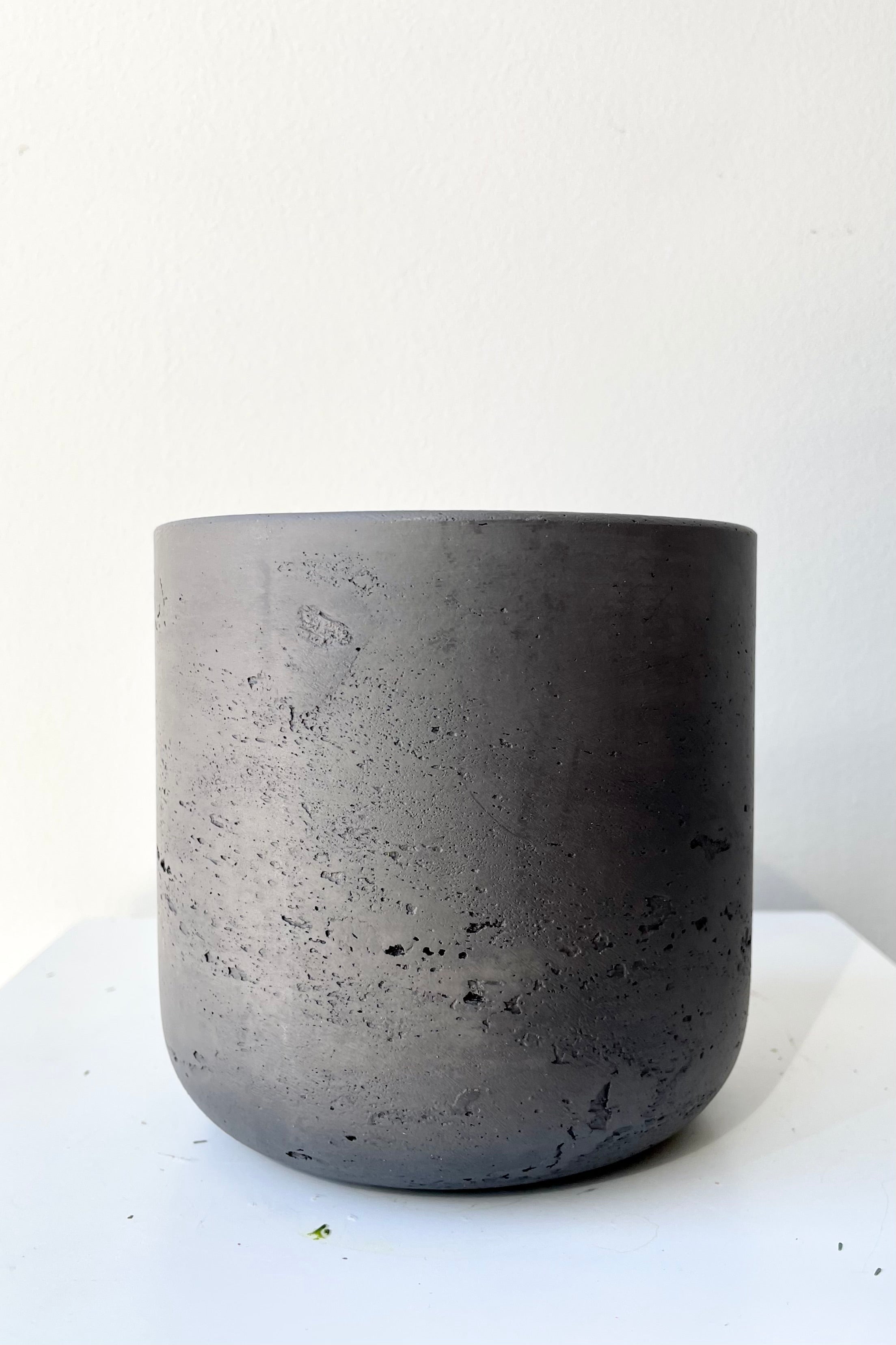 The black washed extra small Charlie pot against a white wall at Sprout Home.