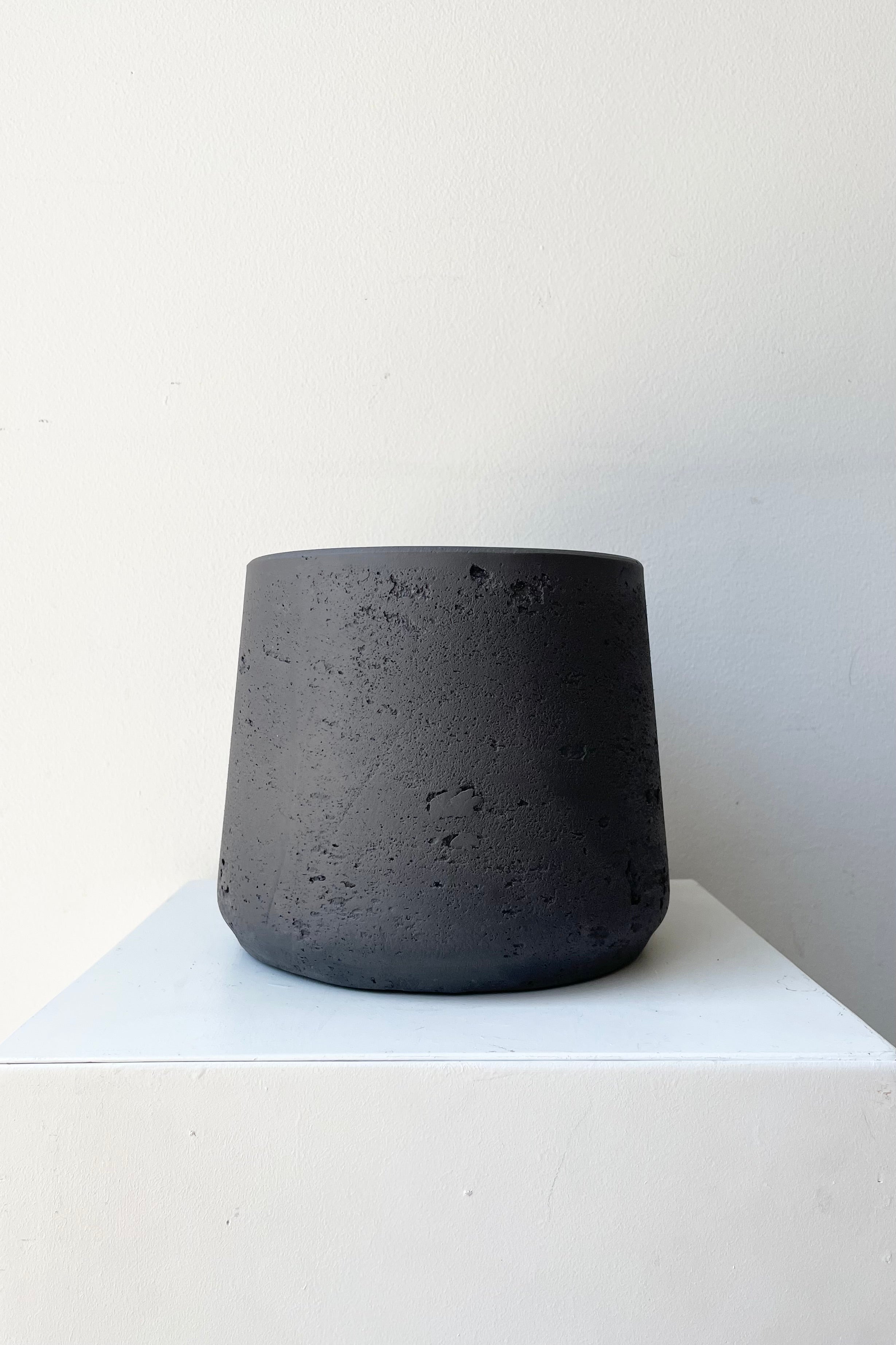Patt Pot black Washed Medium against a white wall