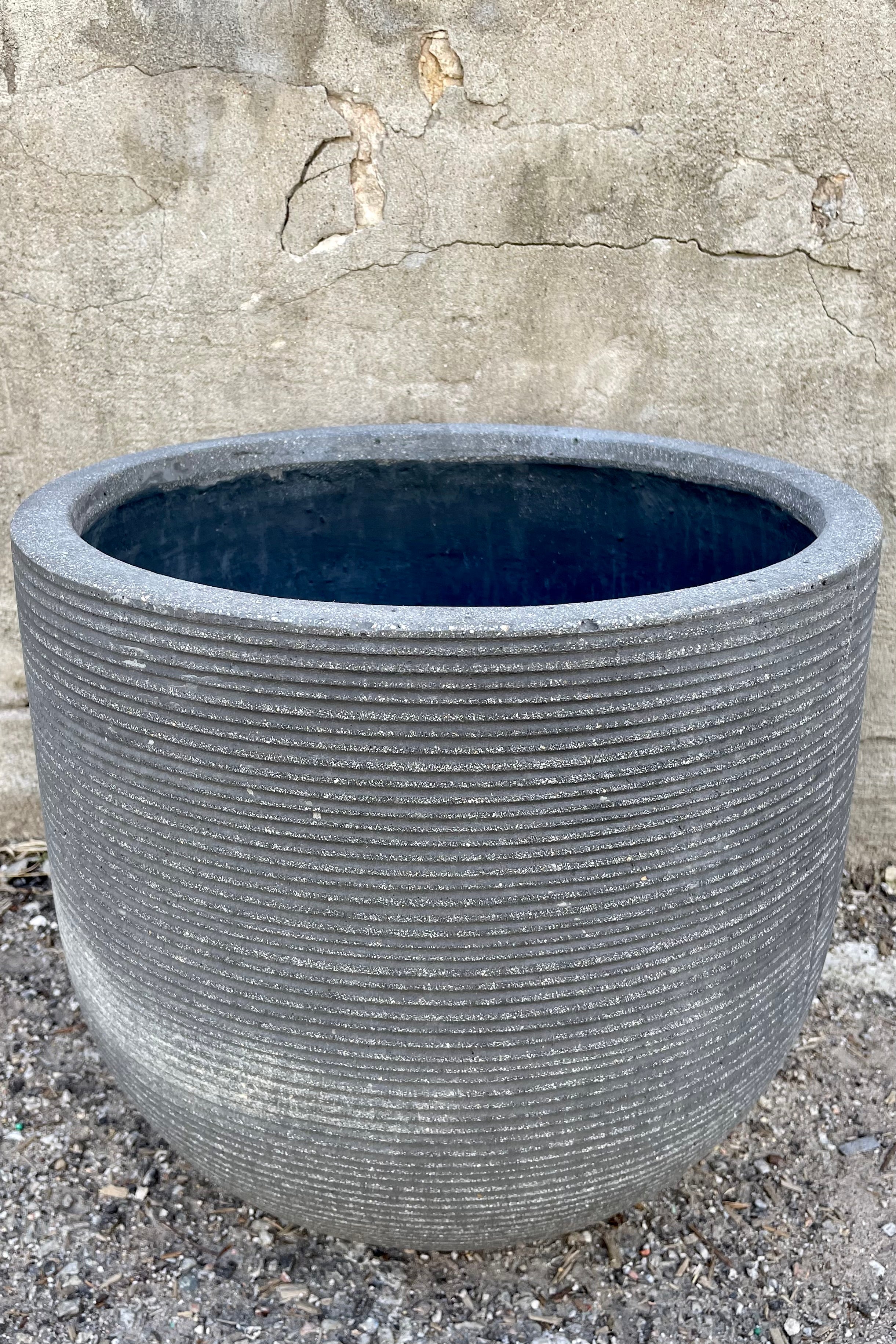 Detail of Cody Pot horizontal ridged dark grey large against a grey wall