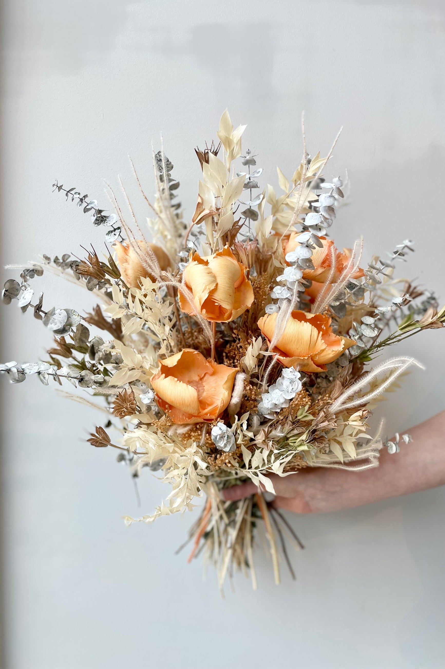 A hand holds the $200 option of Preserved Arrangement Creamsicle by Sprout Home against a white backdrop ©Sprout Home #size_$200