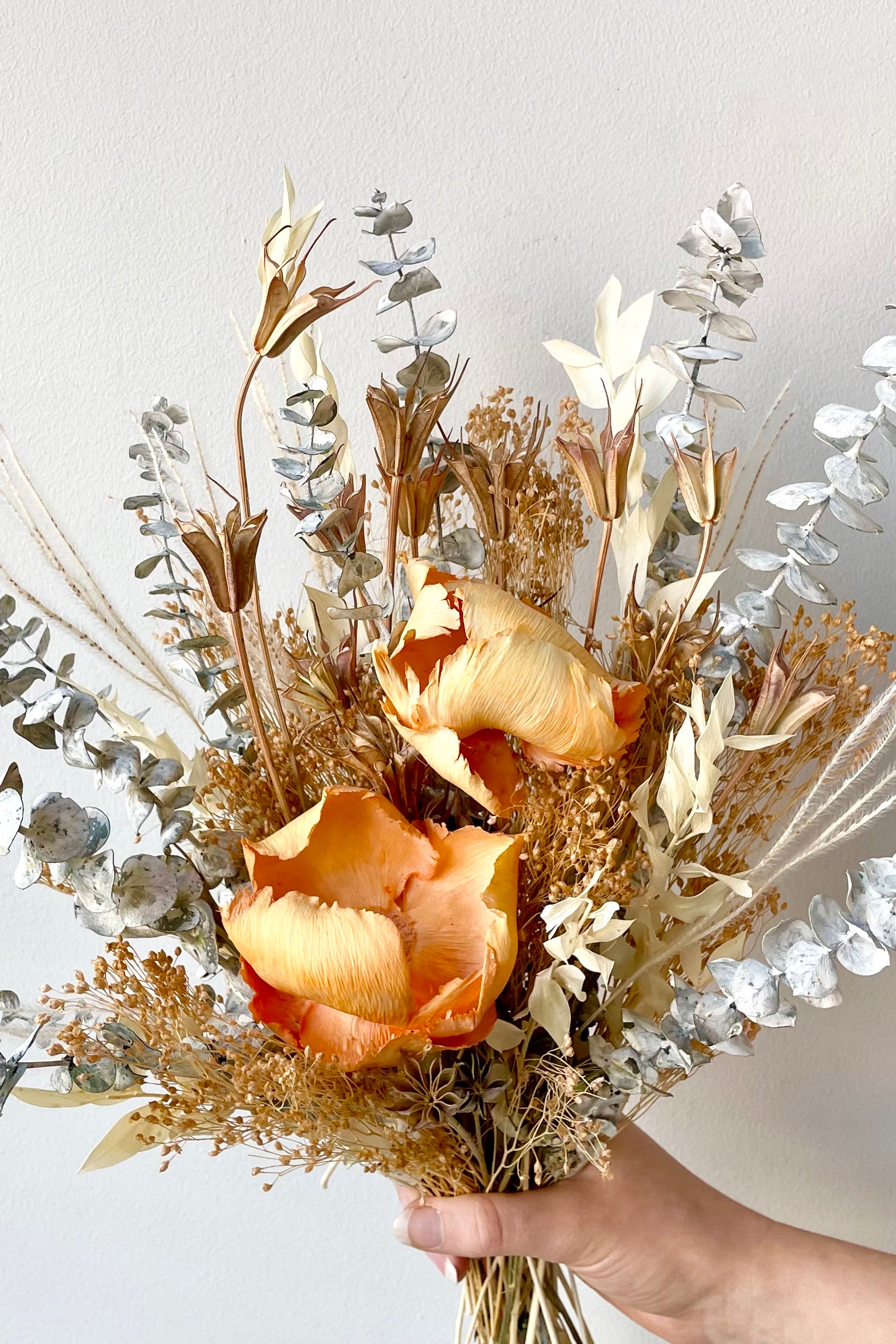A hand holds the $60 version of Preserved Arrangement Creamsicle by Sprout Home #size_$60
