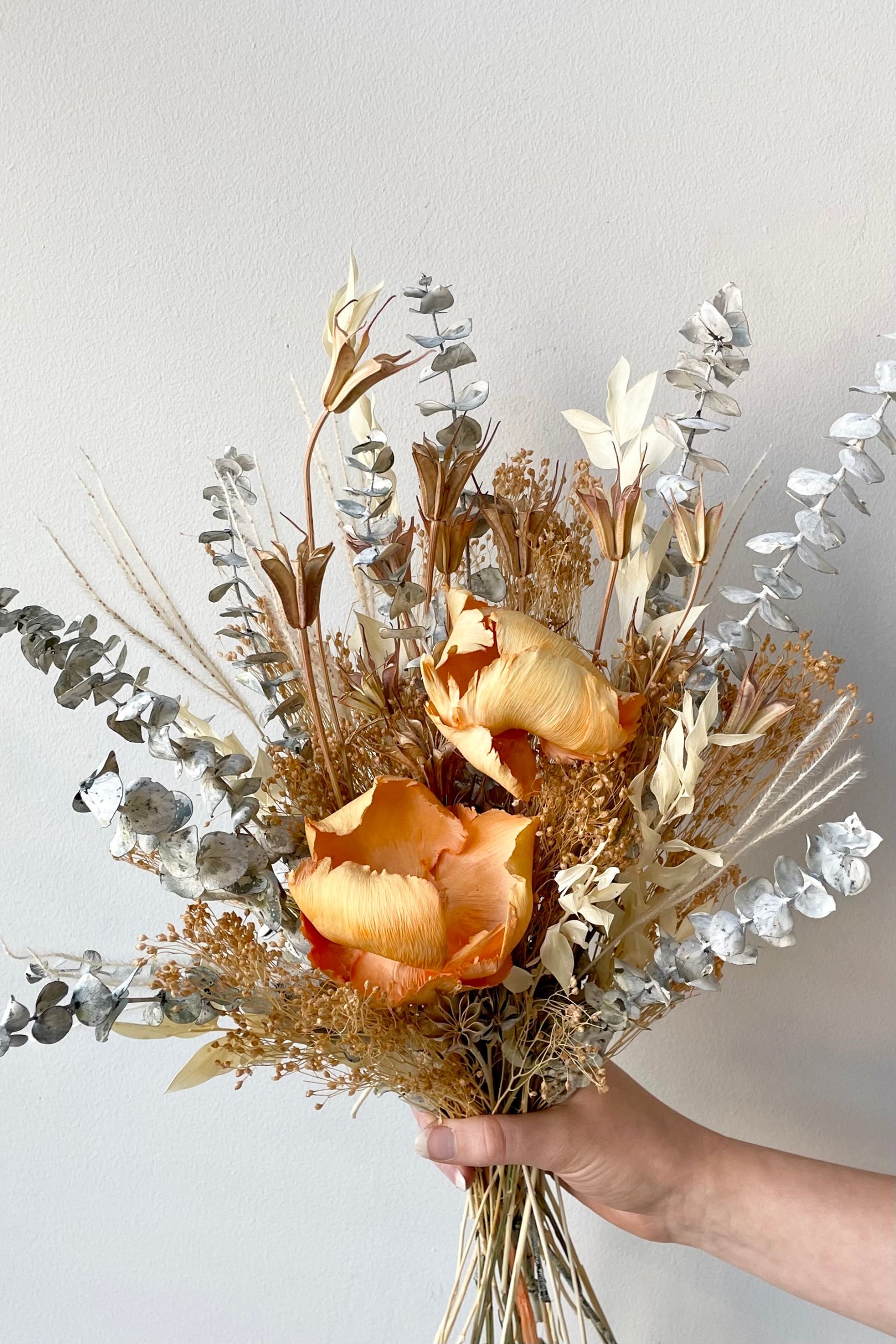 A hand holds the $60 version of Preserved Arrangement Creamsicle by Sprout Home against a white backdrop©Sprout Home #size_$60