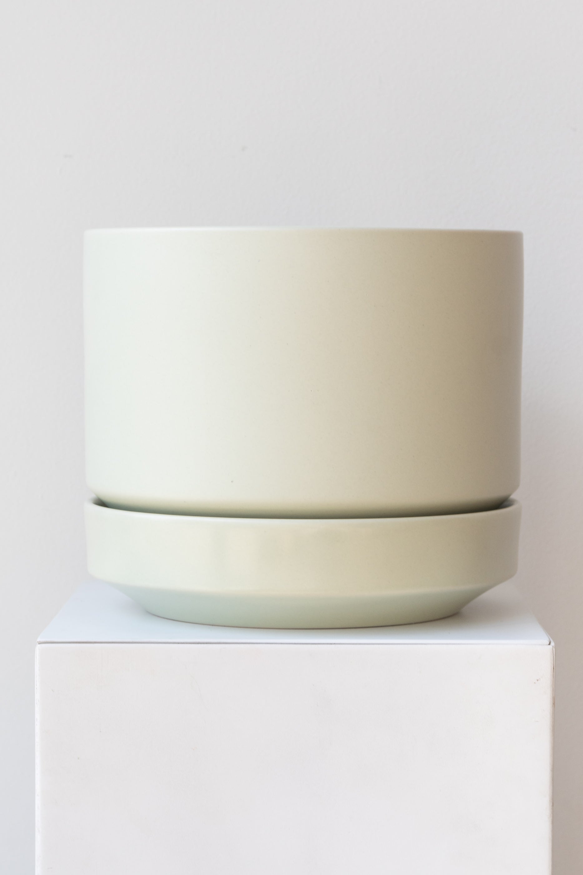 LBE Designs Round Pot & Saucer mint on a white pedestal in a white room
