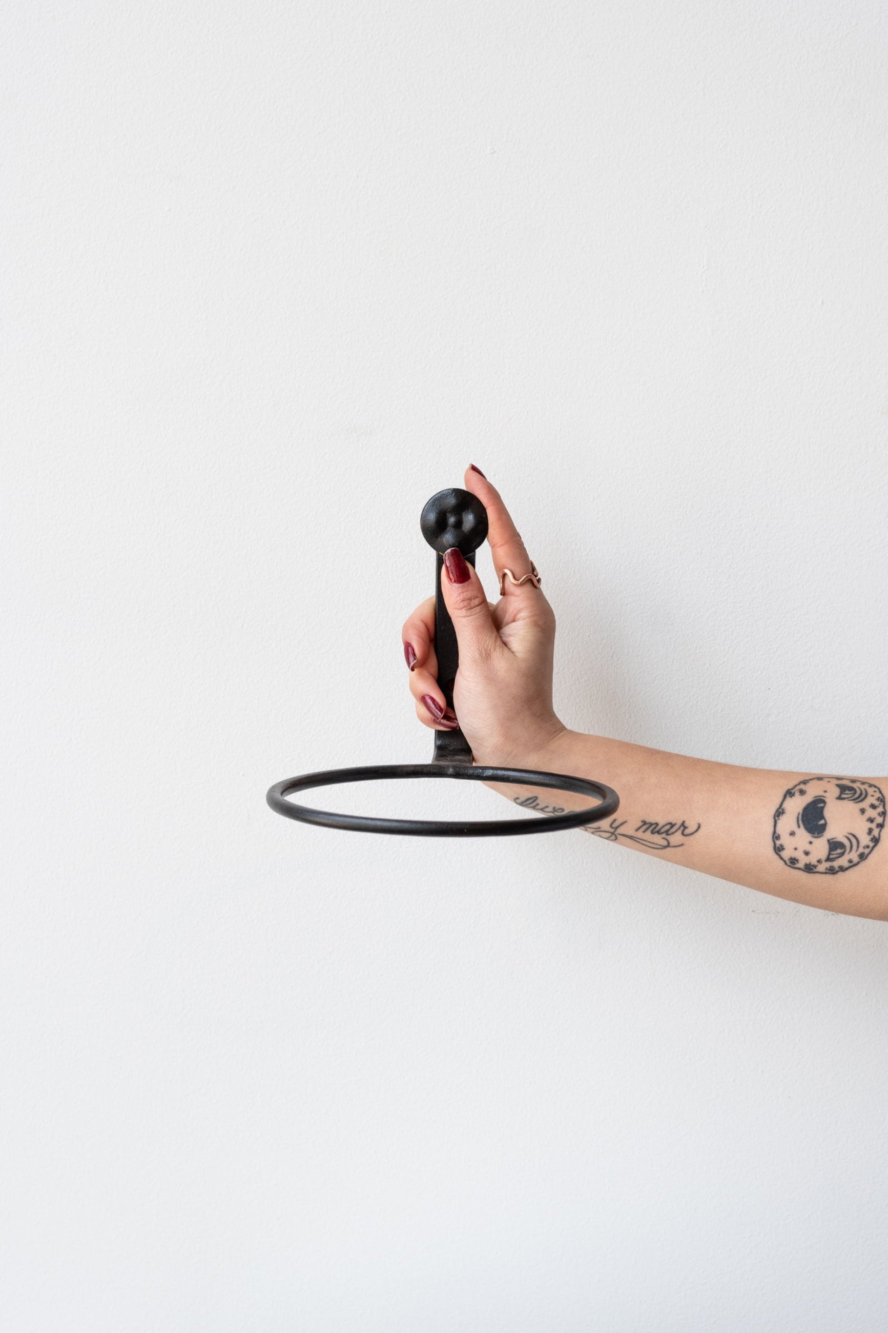 Tattooed arm with red nails holding 6 inch black flowerpot ring by Achla