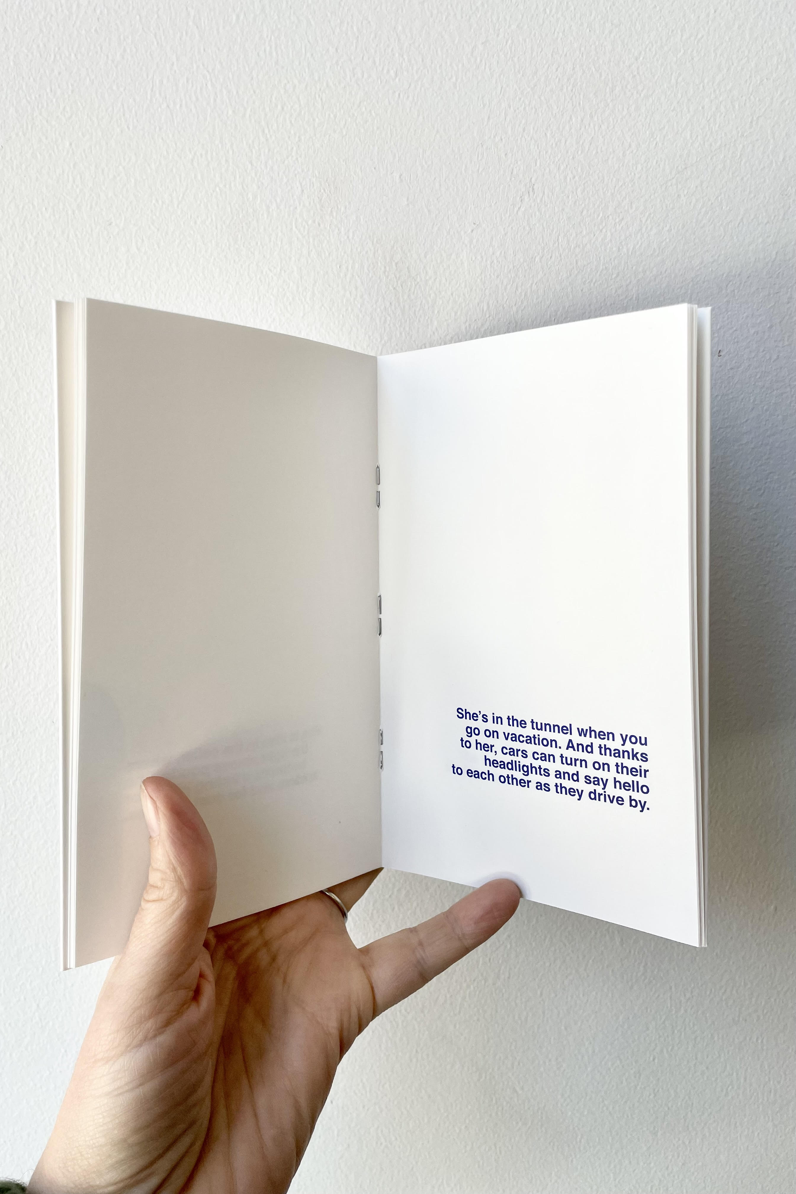 A hand holds a page open of What Happens To Night...? - Book to Illustrate.