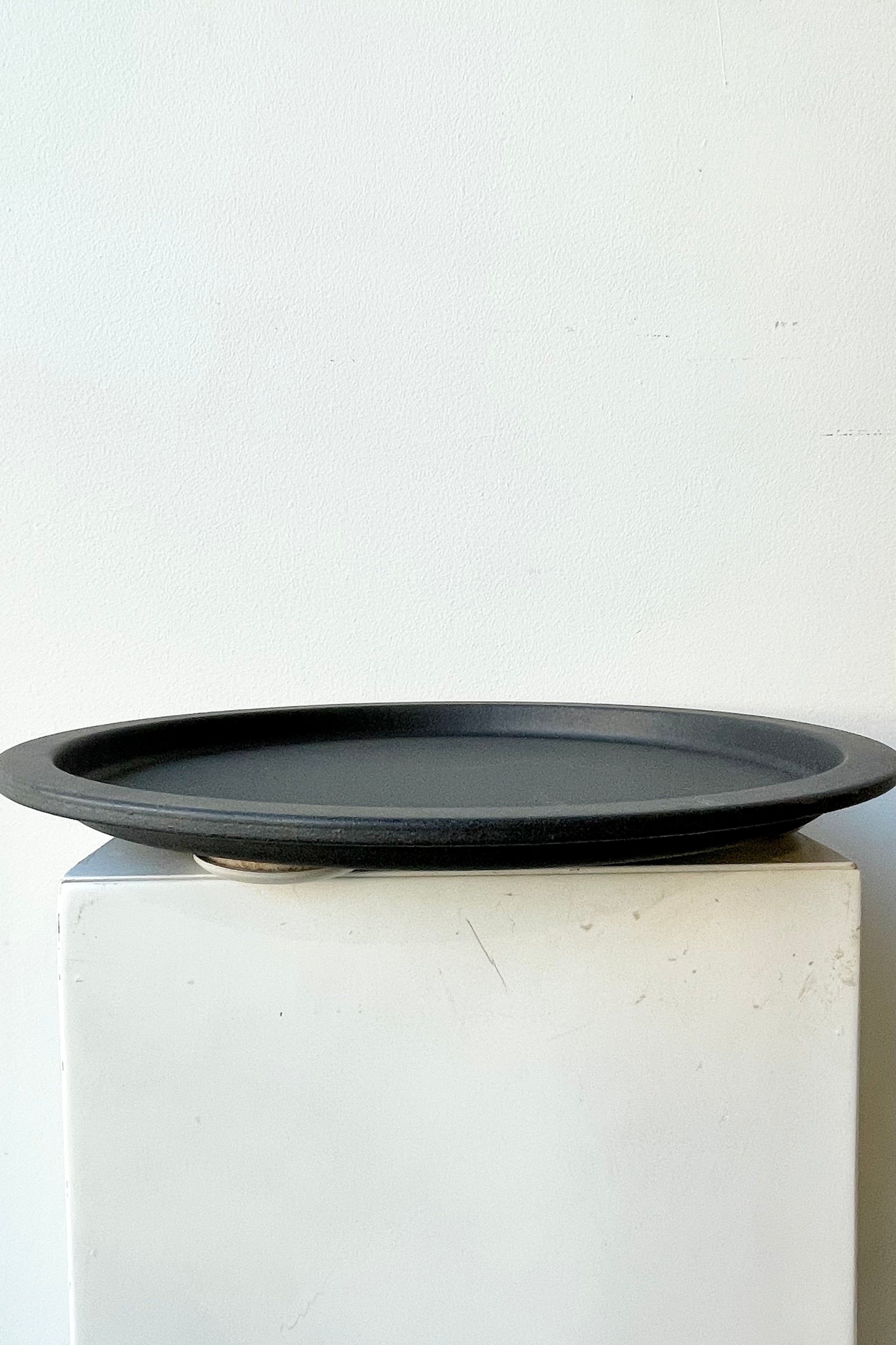 The grey speckled saucer against a white wall at Sprout Home
