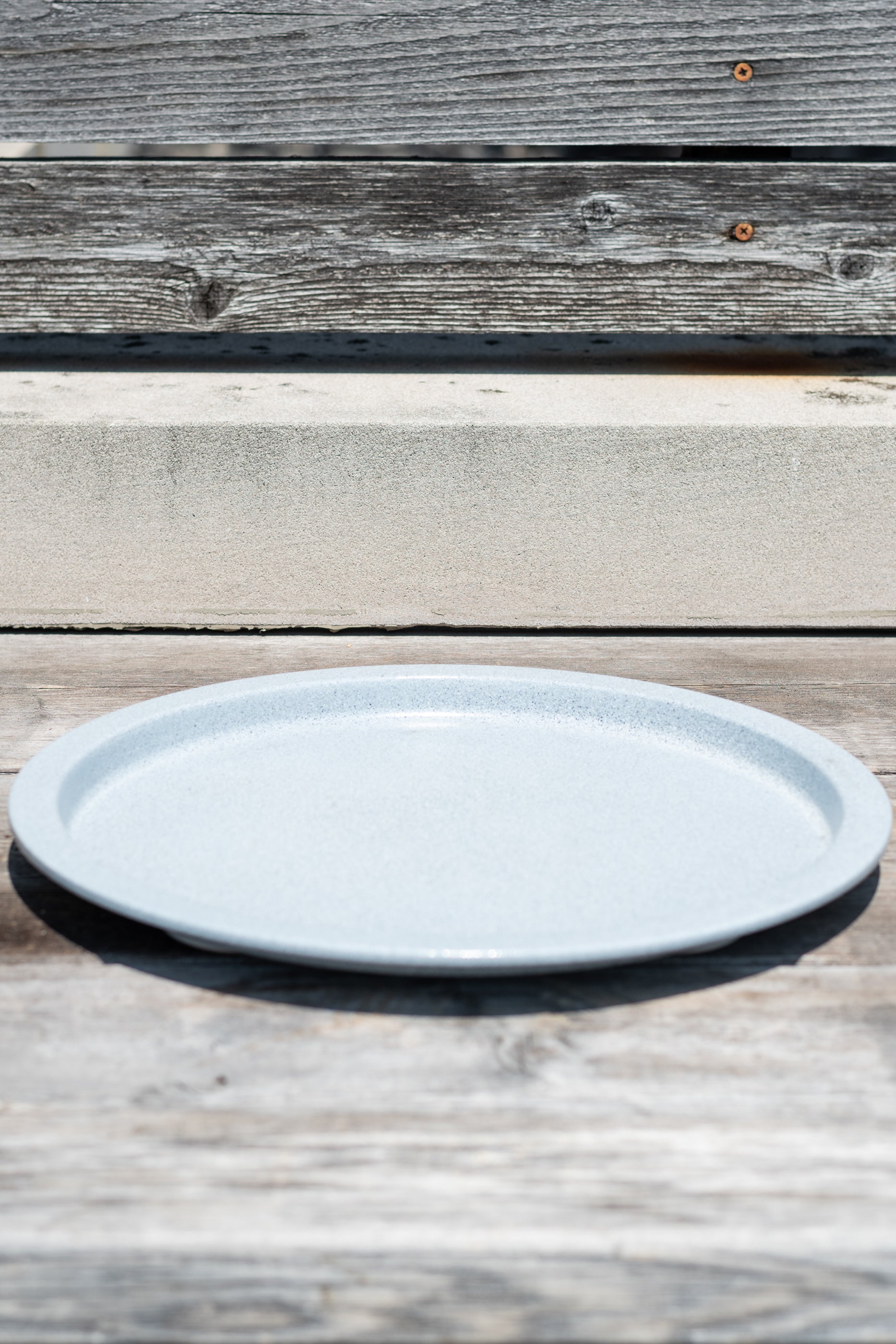 13" multi granite metal plant saucer on a grey wood surface