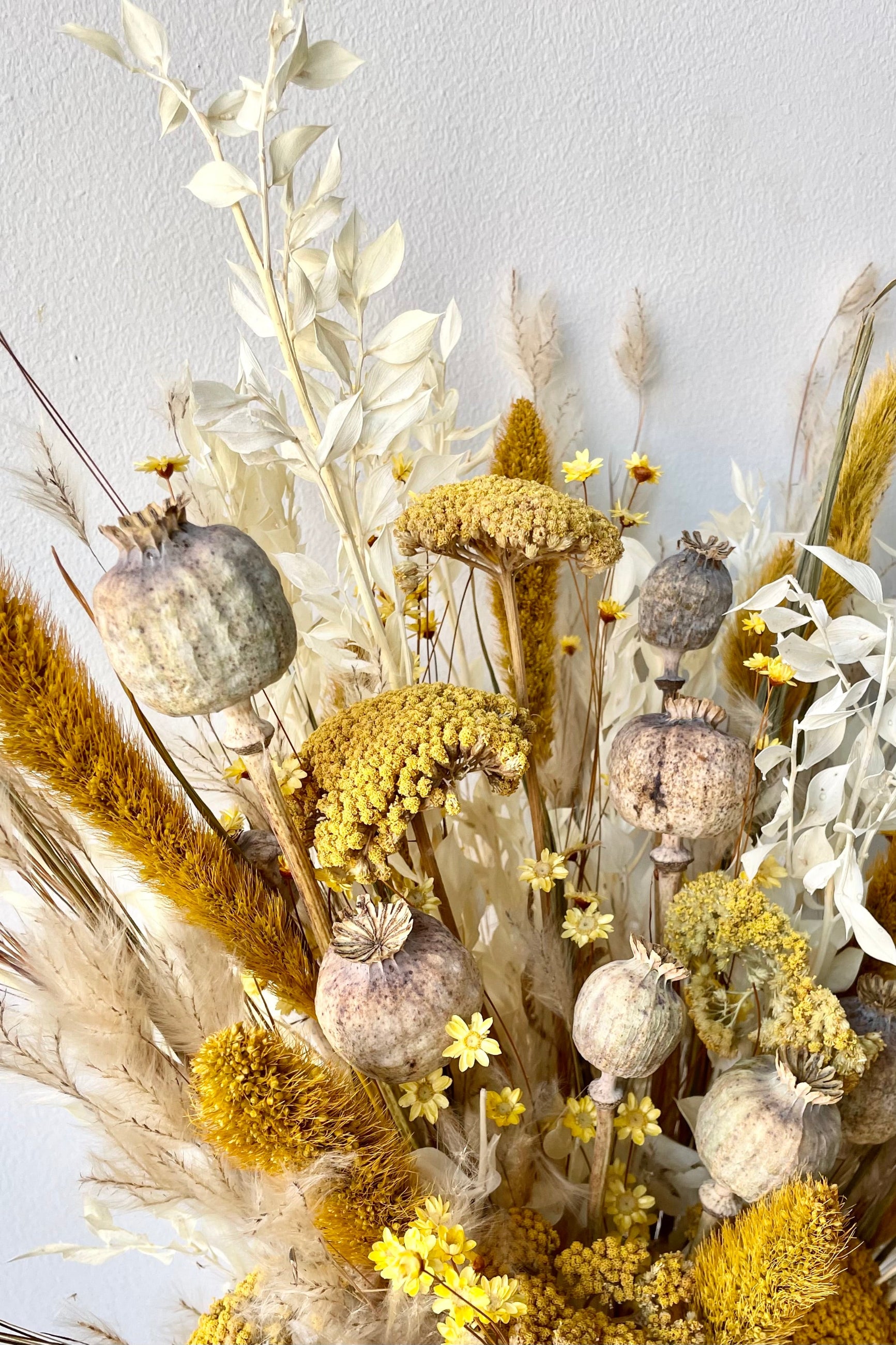 Pops of yellow, white, and tan dried floral arranged in front of white wall. ©Sprout Home #size_$125