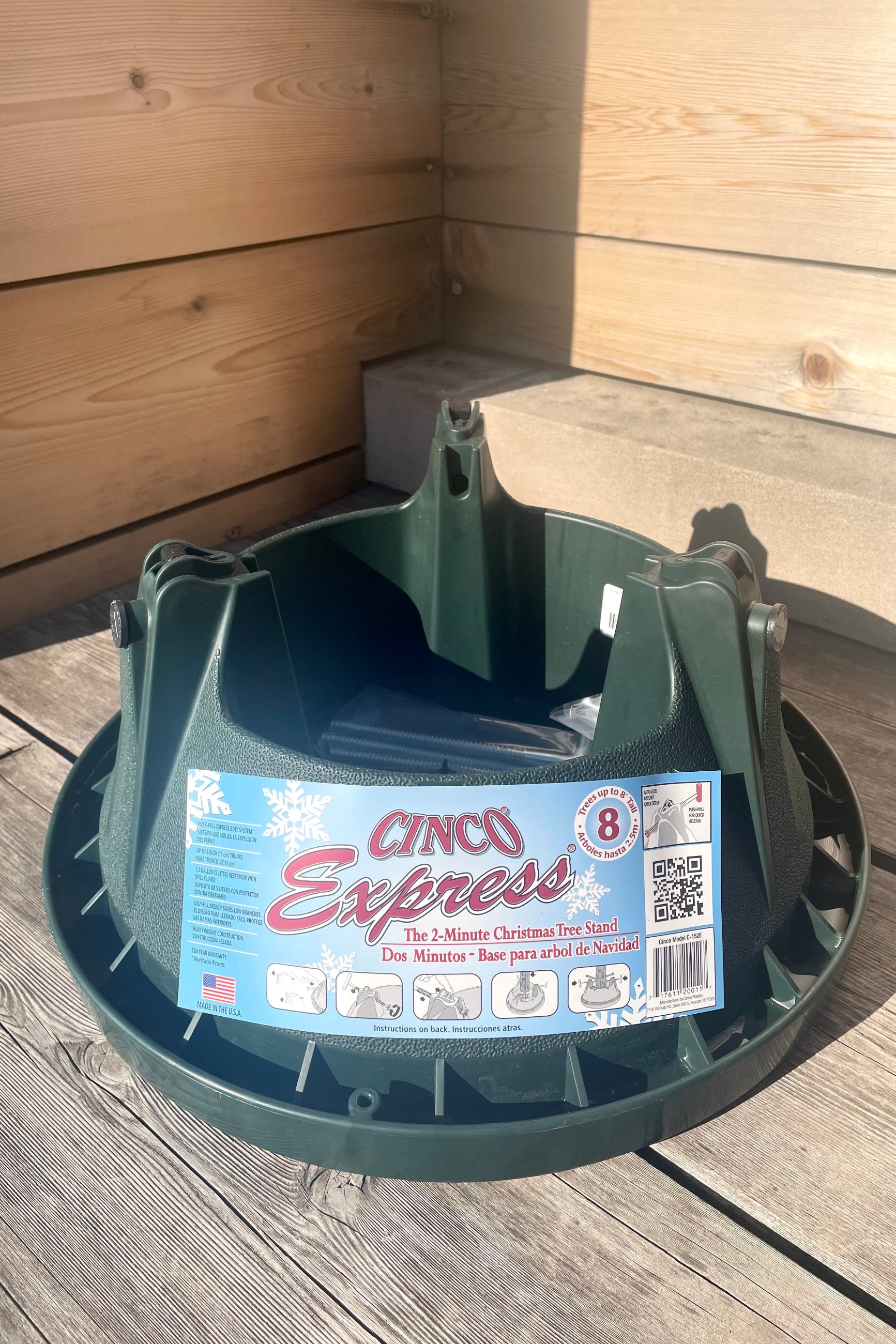 A slight overhead view of the Cinco Xmas Tree Stand up to 8' against a wood backdrop ©Sprout Home