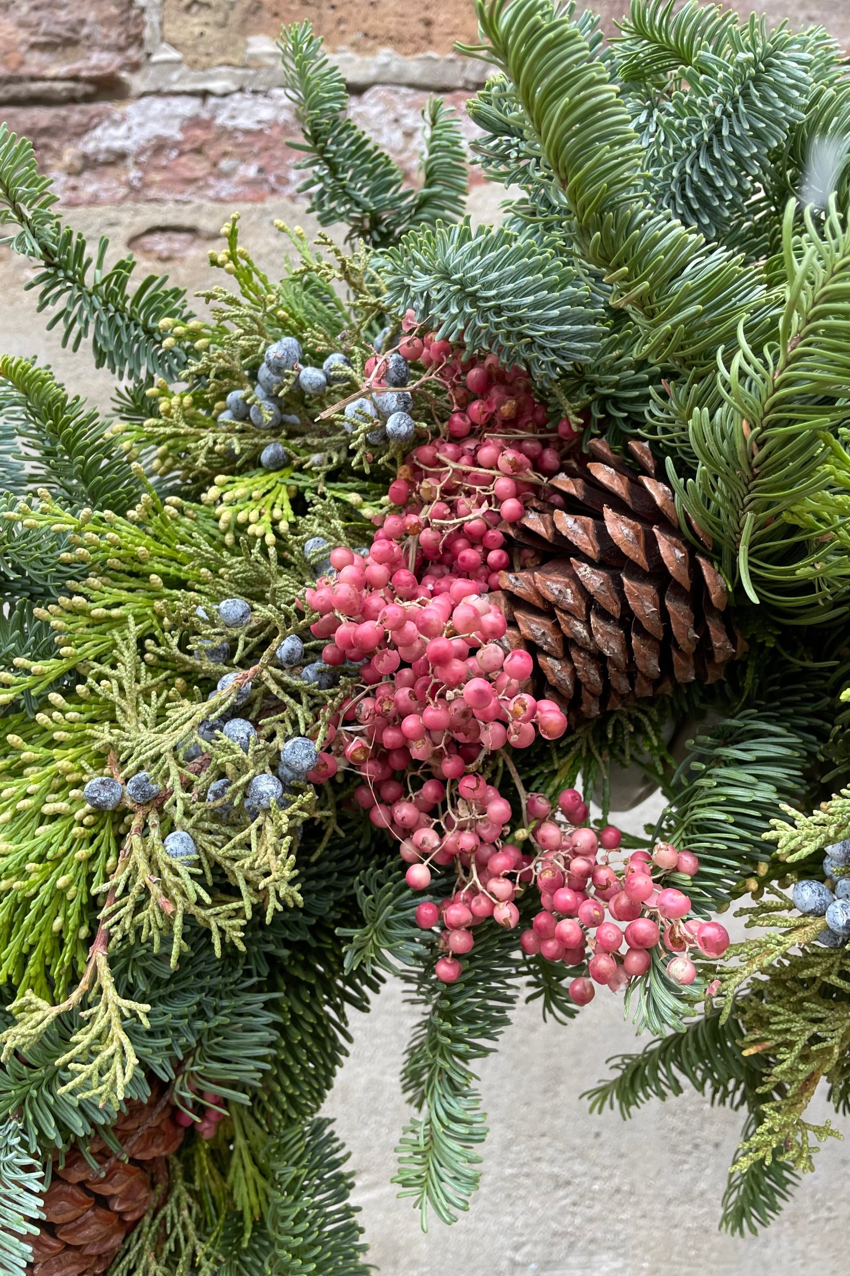 Evergreen wreath detail with pine cone and pepper berry. ©Sprout Home