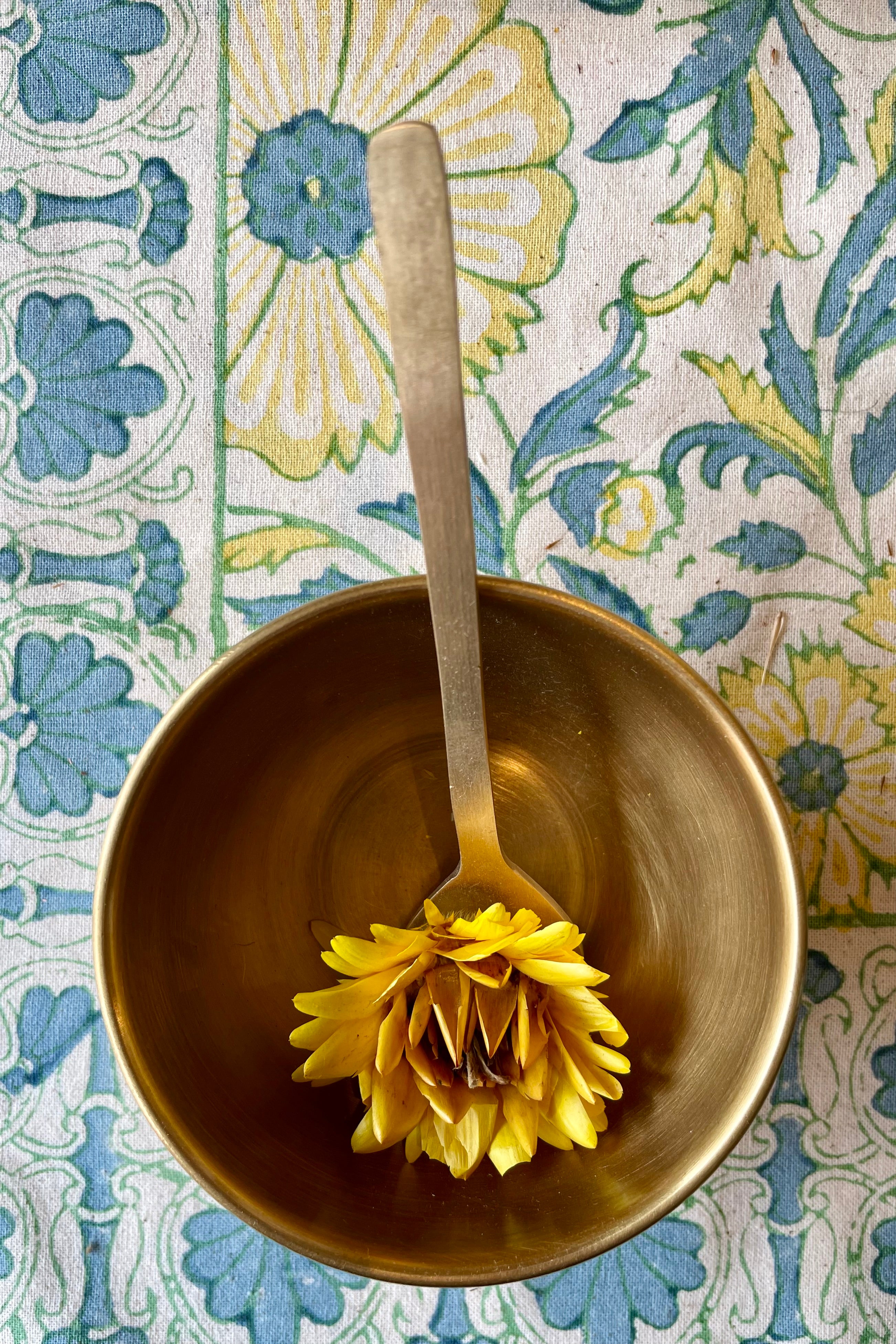 Dessert Spoon brass in a bowl against a table cloth