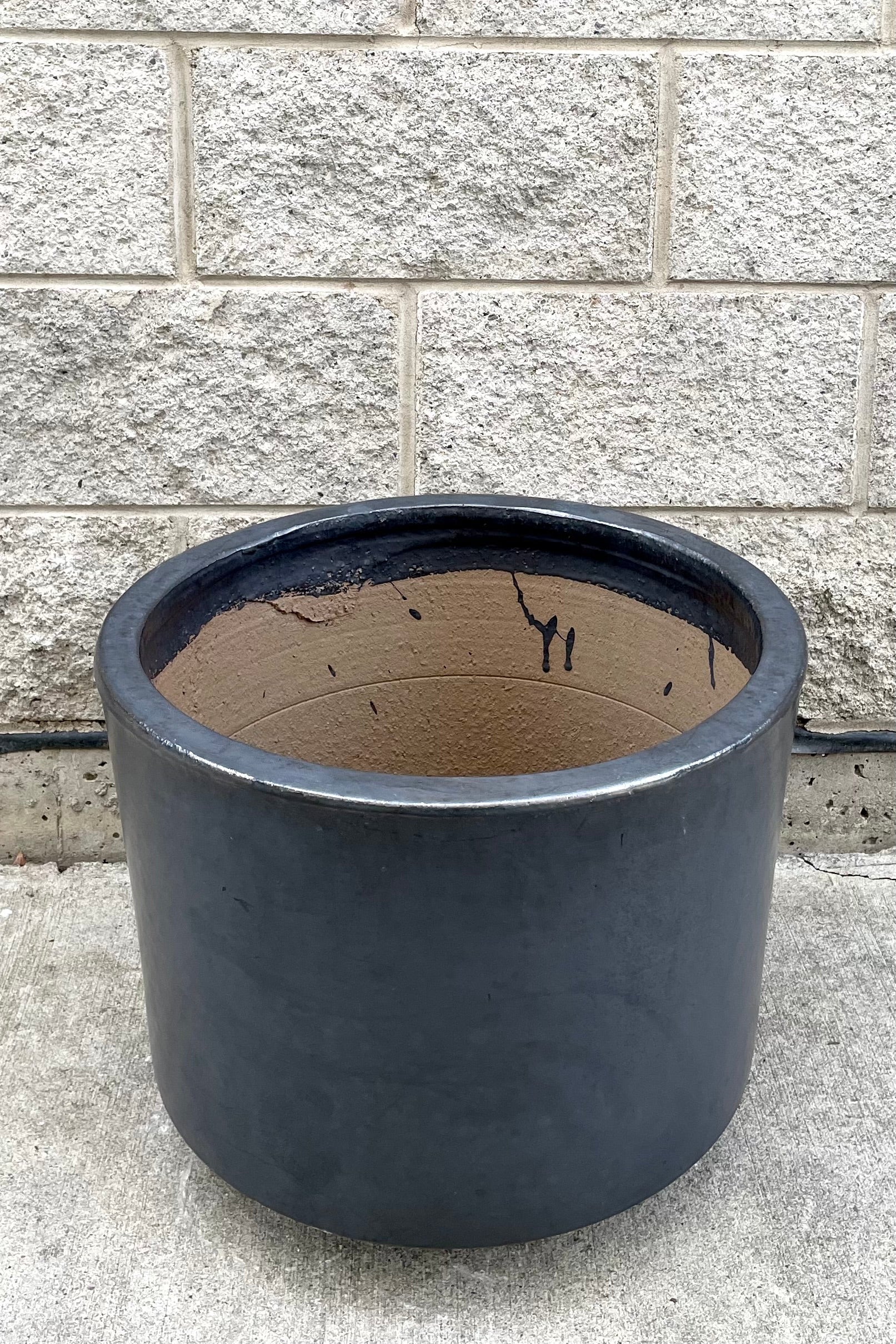 A slight overhead view of Lara Graphite Planter Large against concrete backdrop