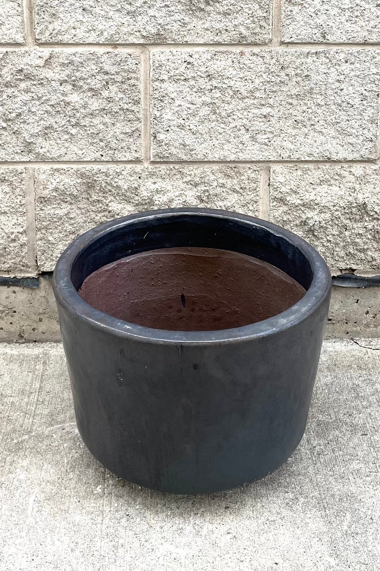 A slight overhead view of Lara Graphite Planter Medium against concrete backdrop