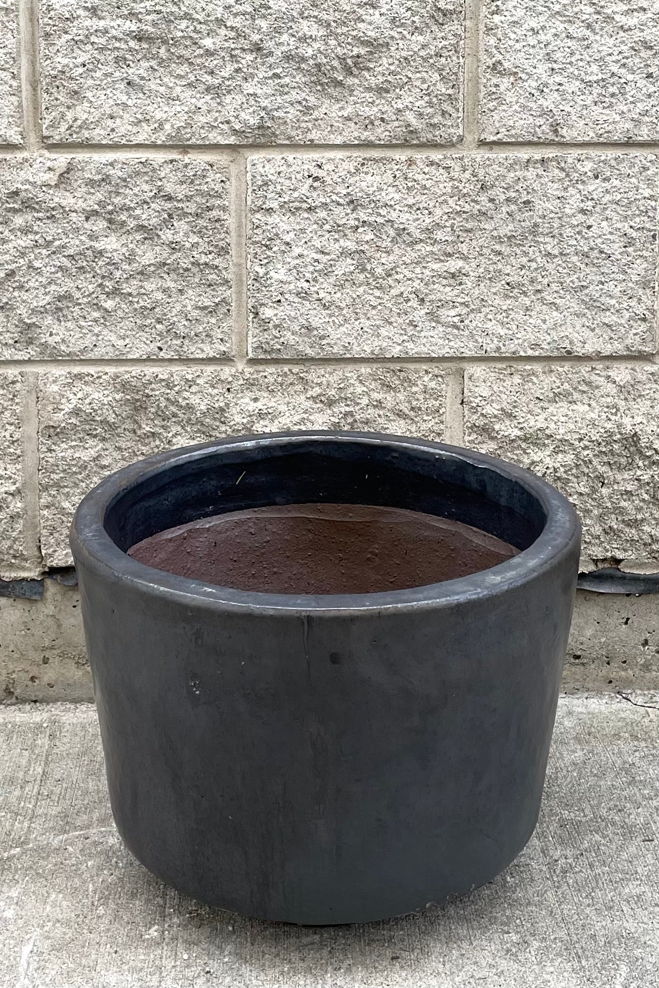 A full frontal view of Lara Graphite Planter Medium against concrete backdrop