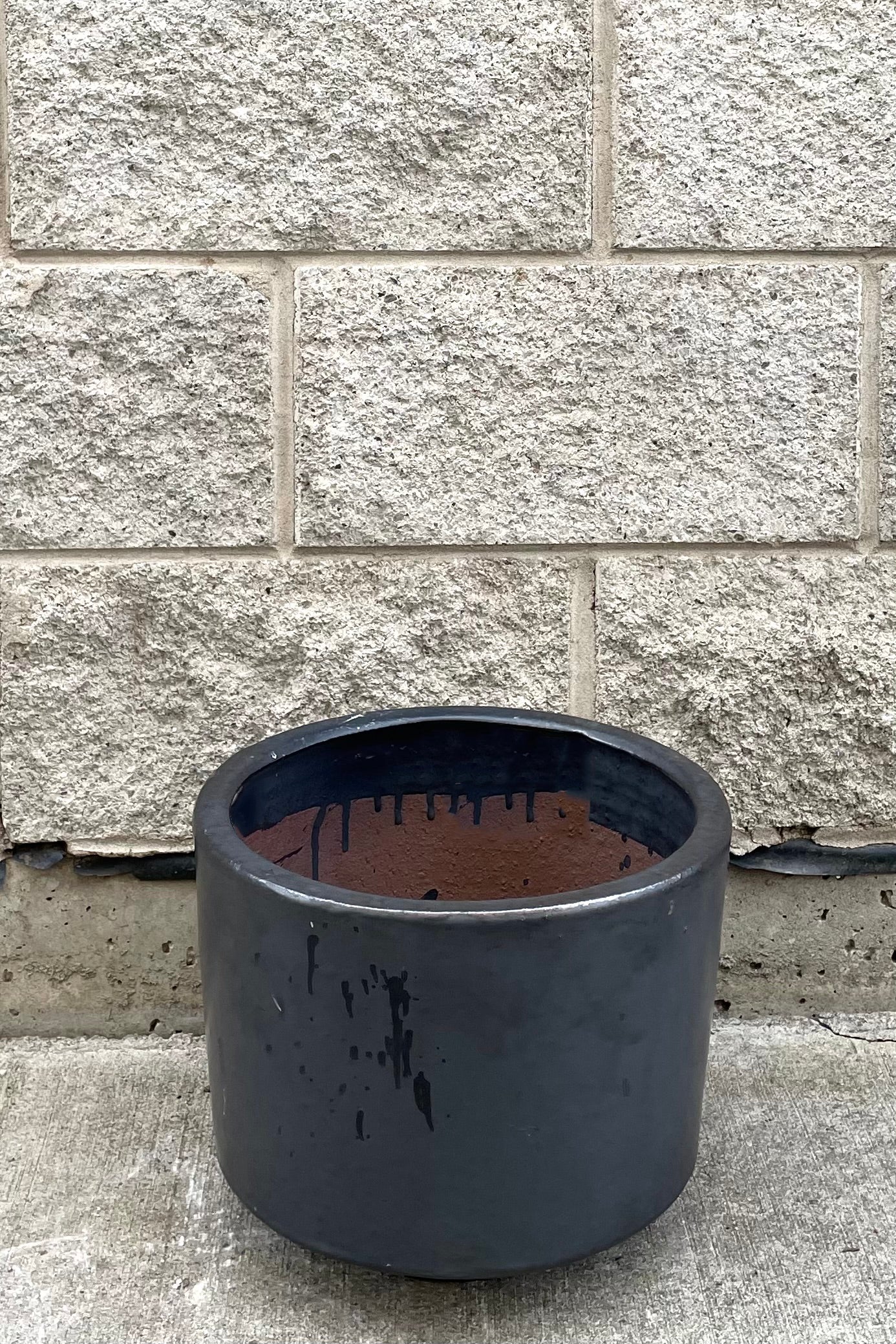 A full frontal view of Lara Graphite Planter Small against concrete backdrop