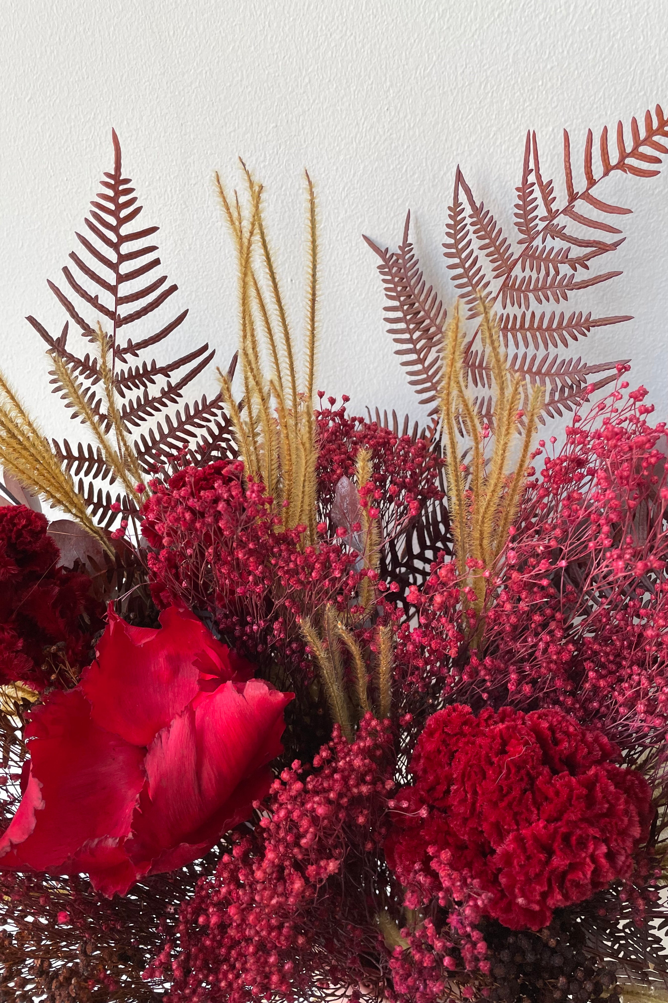 Preserved Red Velvet arrangement detail against a white wall #size_$85
