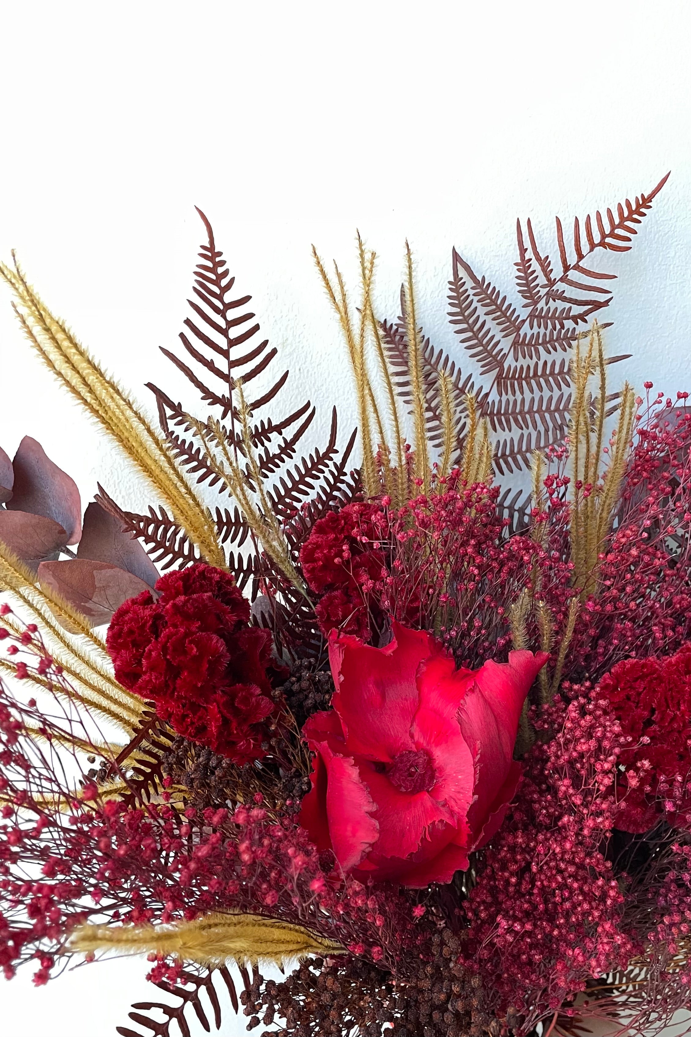 Preserved Red Velvet arrangement detail against a white wall #size_$85