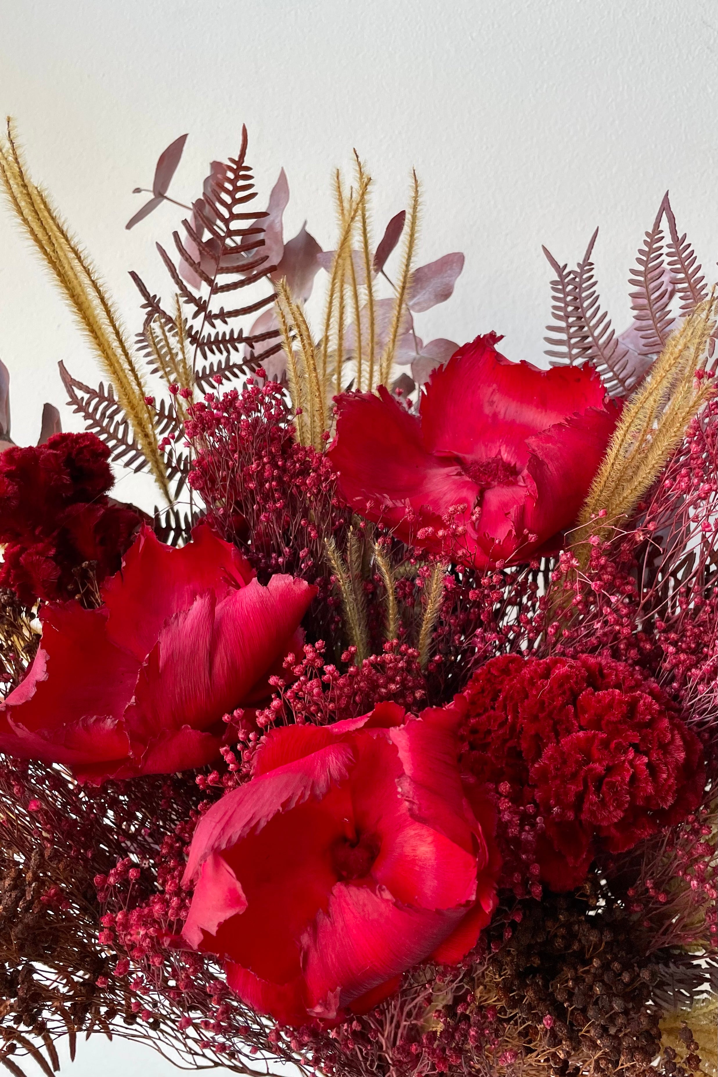 Preserved Red Velvet arrangement detail against a white wall #size_$85