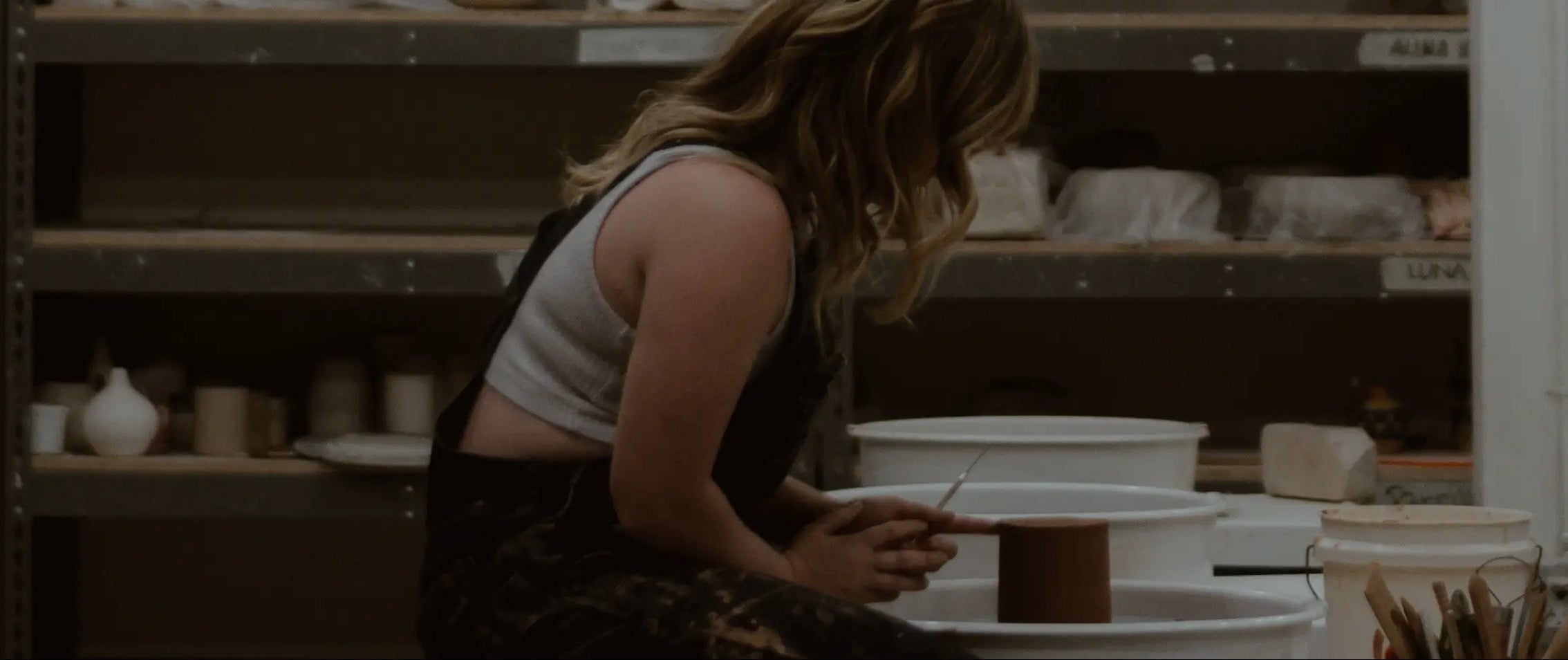 Olivia Snow working in her studio bent over a potting wheel ©Olivia Snow Ceramics