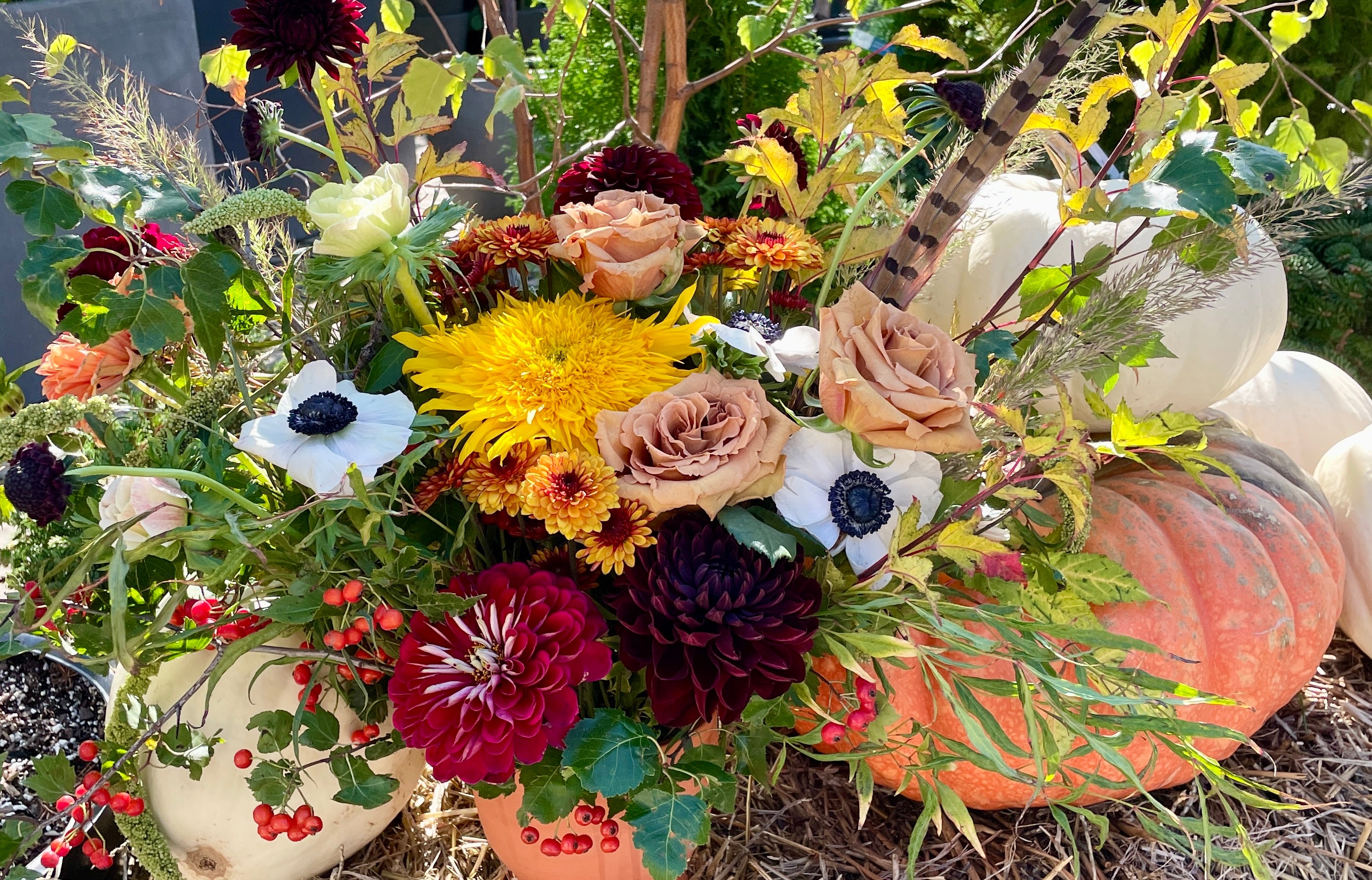 A custom fall floral arrangement sitting on a hay bale with pumpkins in October. 