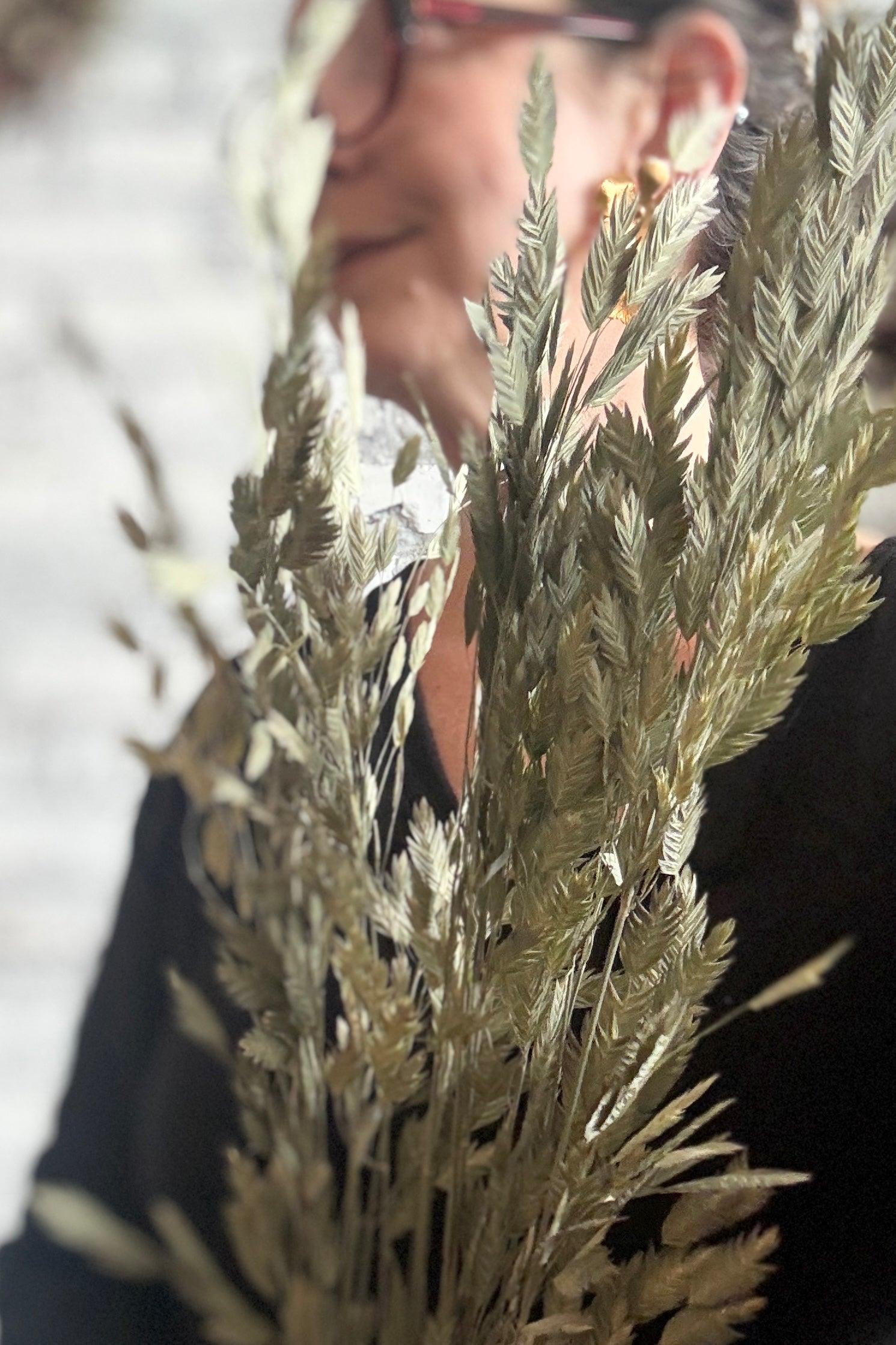 Person holding a bouquet of dried Chasmanthium grass with a blurred background ©Sprout Home