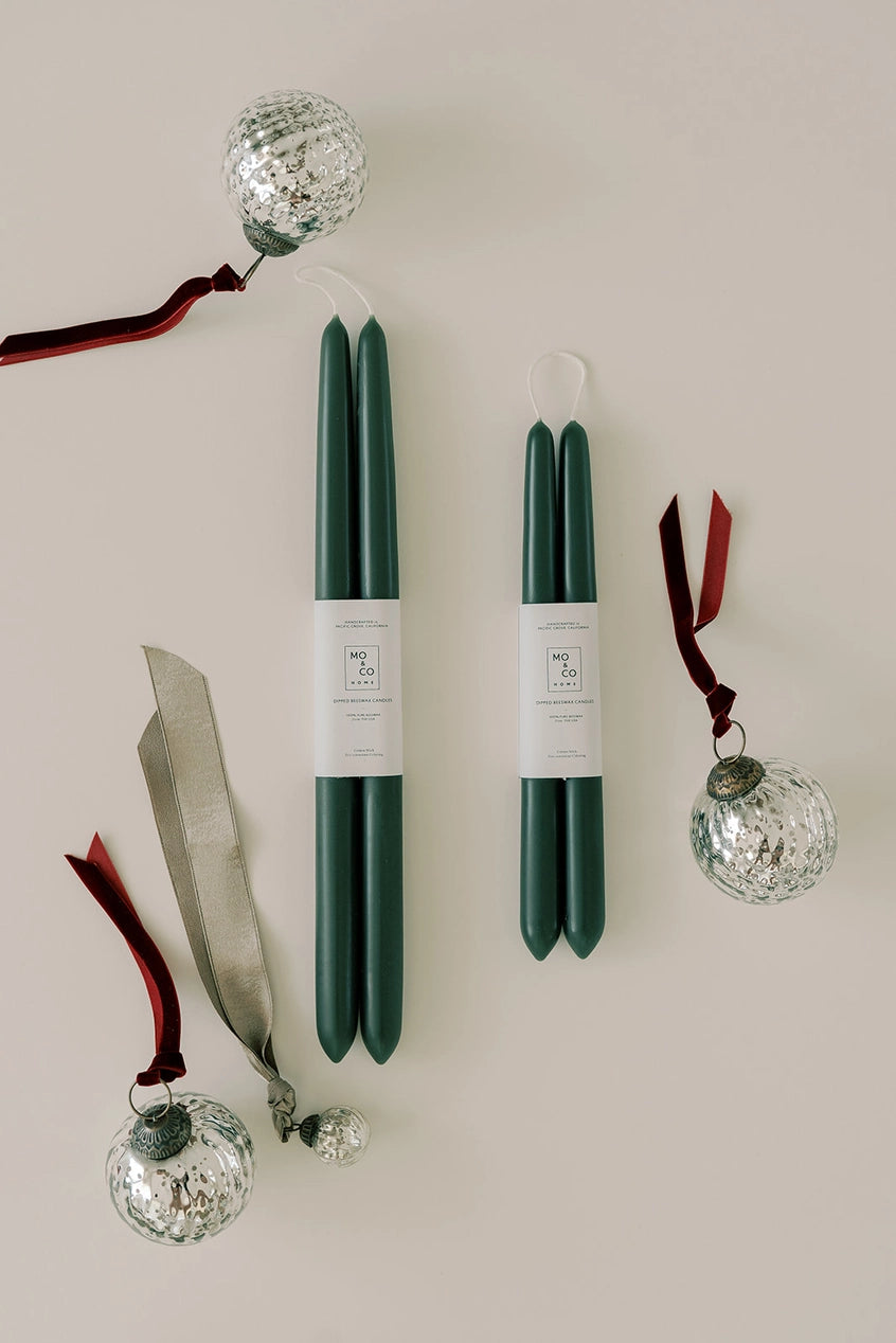 Mo & Co beeswax taper candles in Forest Green two pairs of different sizes shown with clear glass ornaments.