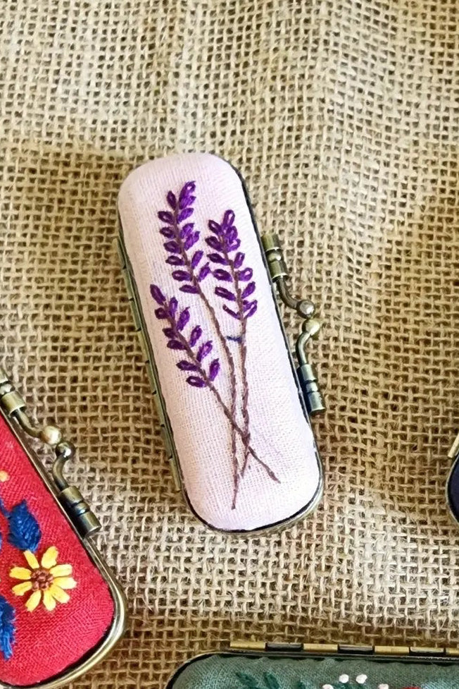 Set of small embroidered cases on a textured fabric background ©Quince Fables