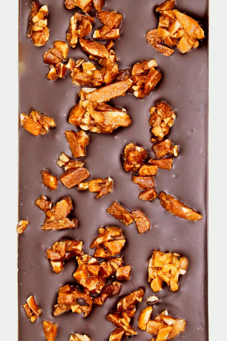 Chocolate bar with chopped nuts on a white background ©Deux Cranes