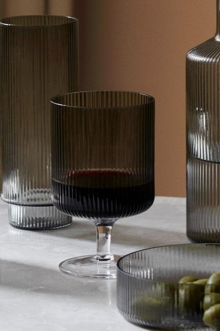 One Smoked Grey wine glass with red wine and other Ripple collection pieces around it. 