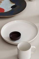 Sekki Cream Large Plate by Ferm Living in the center with another brown dish on top behind a Sekki Mug.