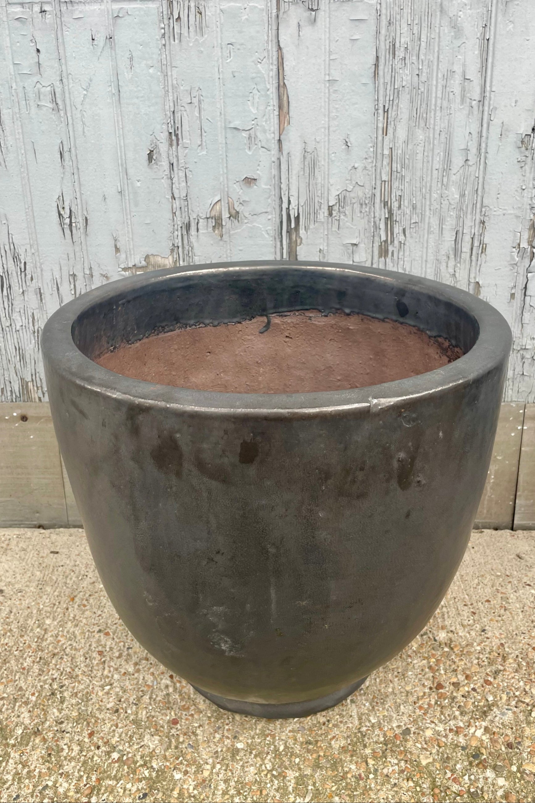 A dark gray planter shown in front of a wooden wall. Looking down. ©Sprout Home