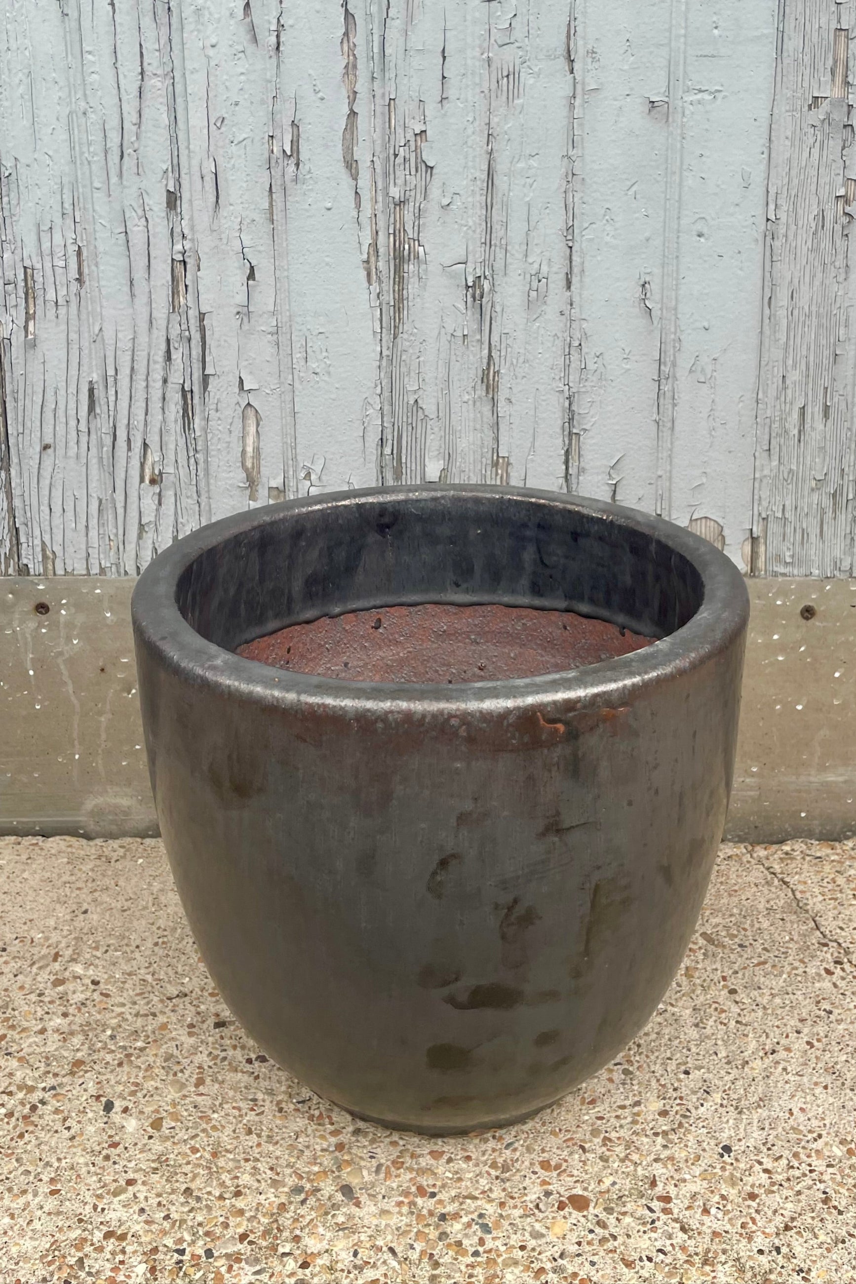 A round black planter in front of a wooden wall looking down ©Sprout Home