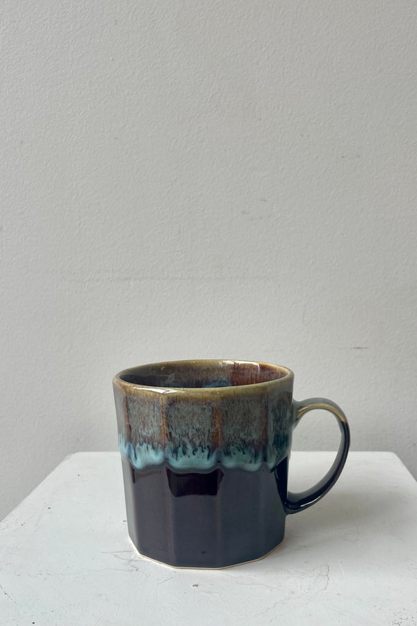 Photo of Arata Mug with black base glaze against a white wall