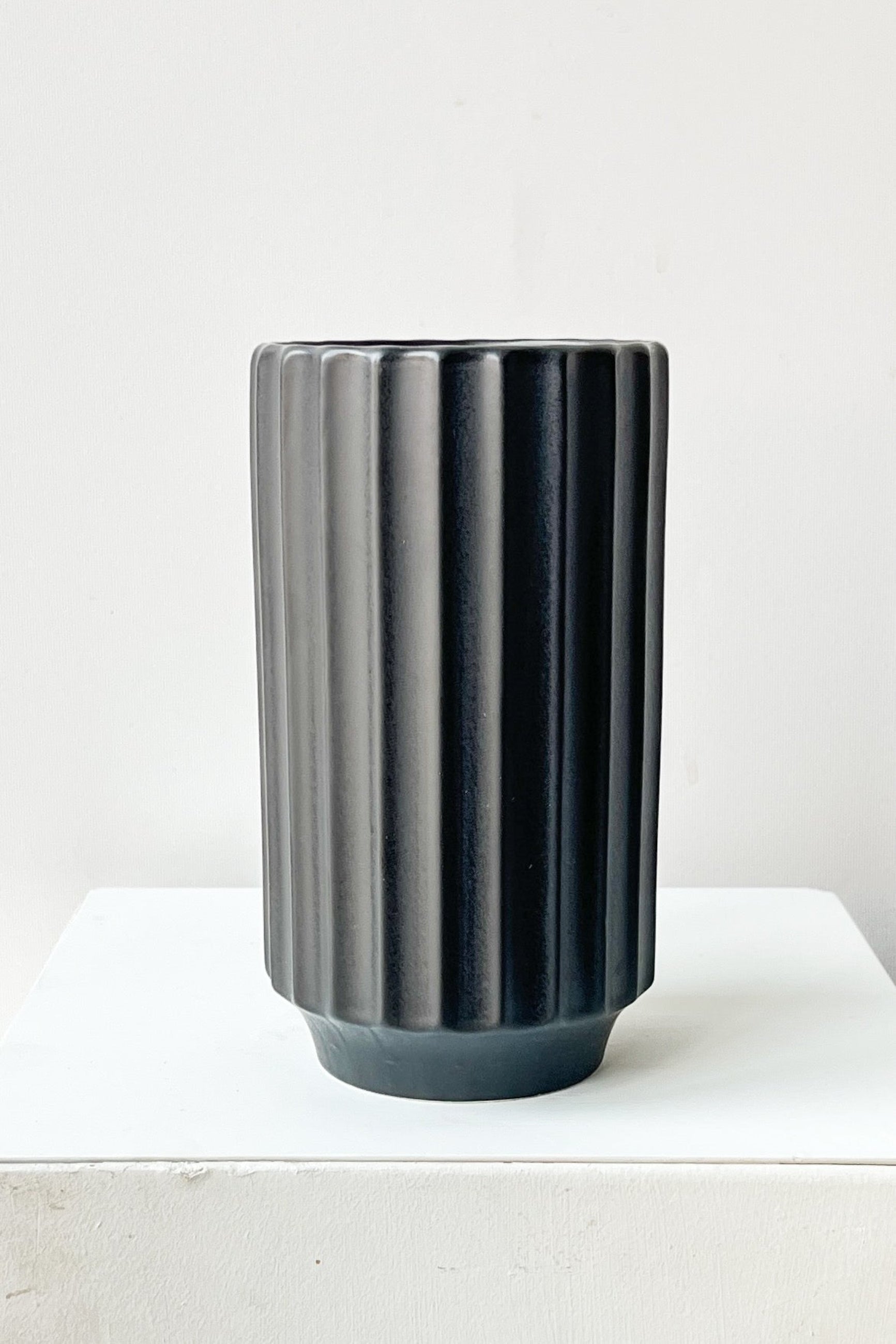 Black ribbed vase on a white surface with a white background ©Sprout Home