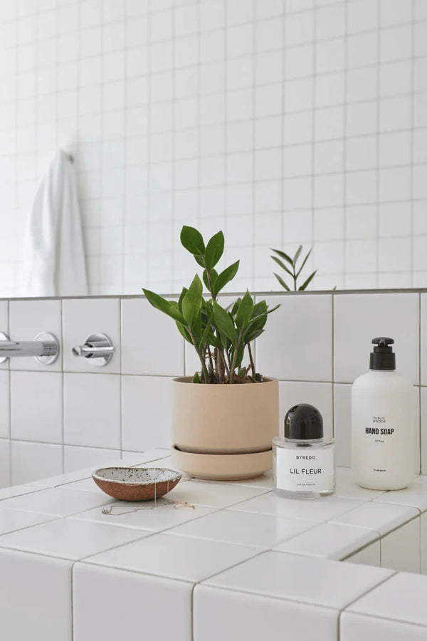 Oatmeal Round Two planter potted with a ZZ plant sitting in a an all white bathroom by LBE Design Revival Ceramics