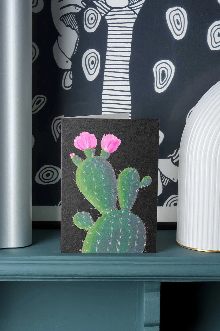 Cactus on Black Greeting card by Stengun Drawings on a shelf with black and white wallpaper.