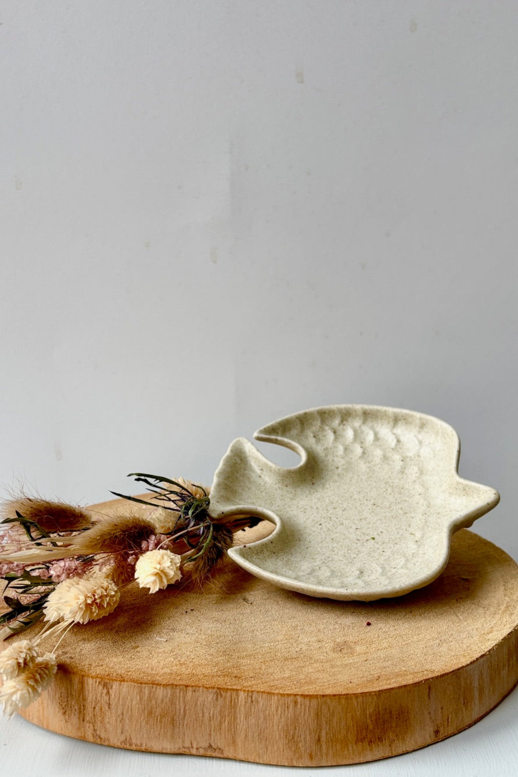 Ceramic bird-shaped dish on a wooden board with dried flowers against a light background ©Sprout Home