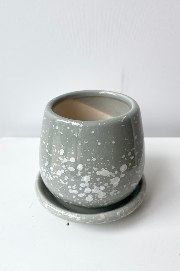 An eggshell small planter in speckled gray looking from the side top seeing a little bit of the interior. 