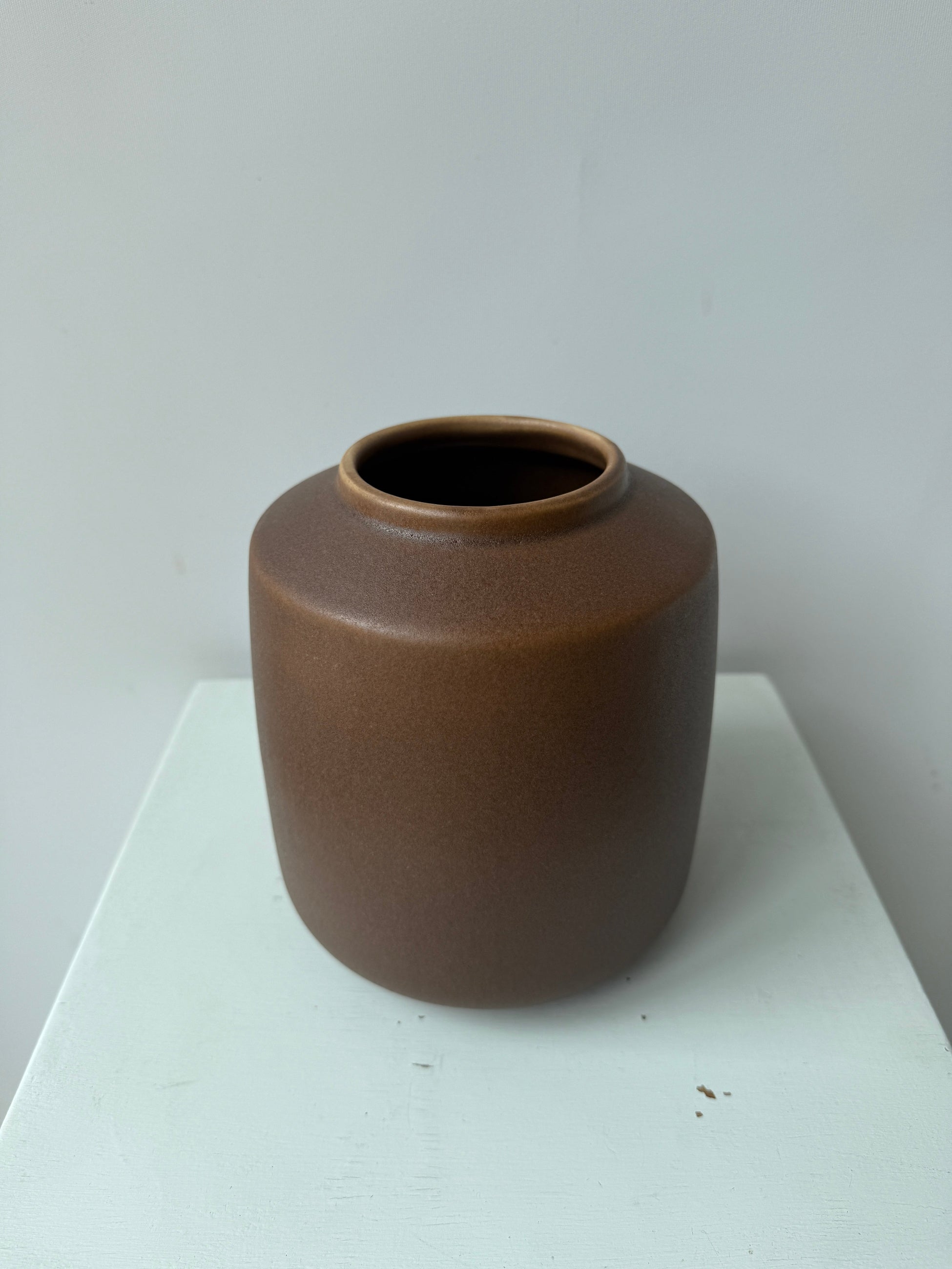 Brown ceramic vase on a white surface with a light gray background ©Sprout Home