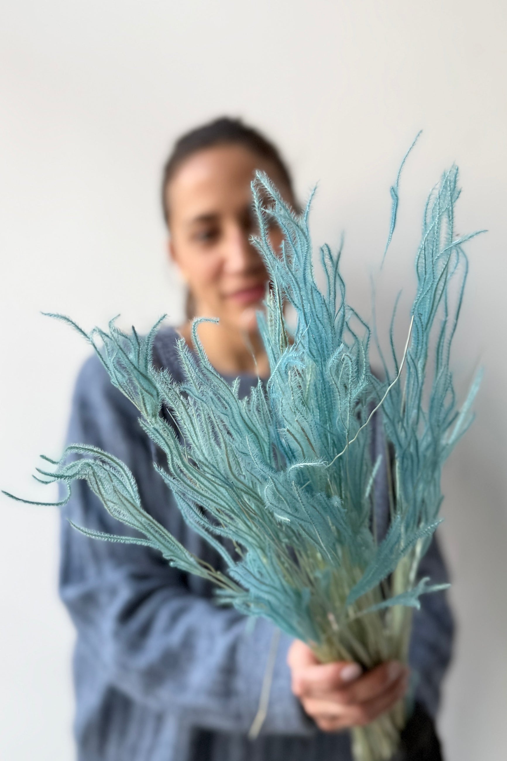 Person holding Ouro Teal Pastel Preserved Bunch against a plain background ©Sprout Home