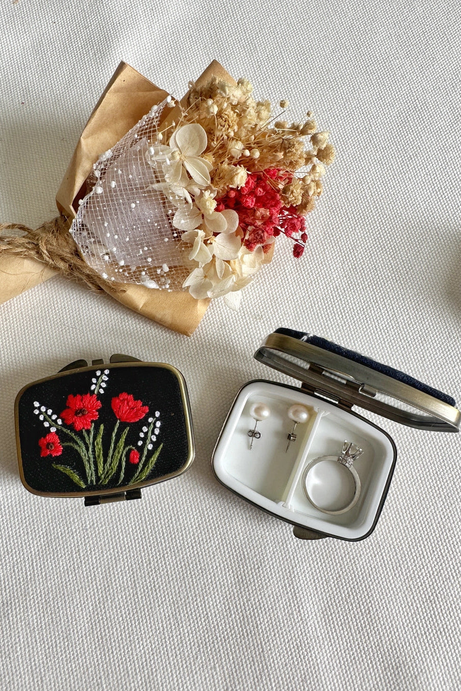 Compact mirror with floral design next to a small jewelry box on a light background ©Quince Fables