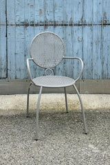 The gray bistro chair at sprout home against a blue gray wood wall. 