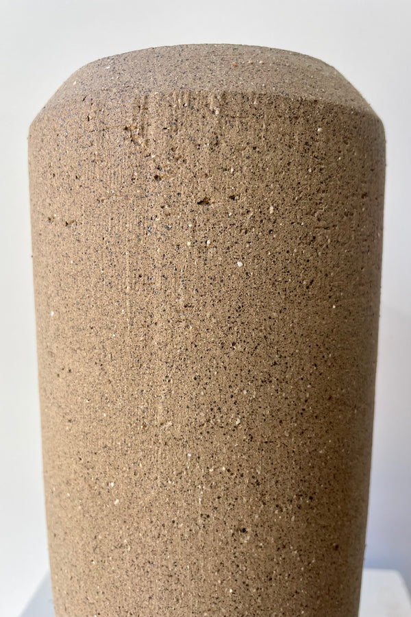 Close photo of the natural rough texture of the brown clay of Valedez vase against a white wall.