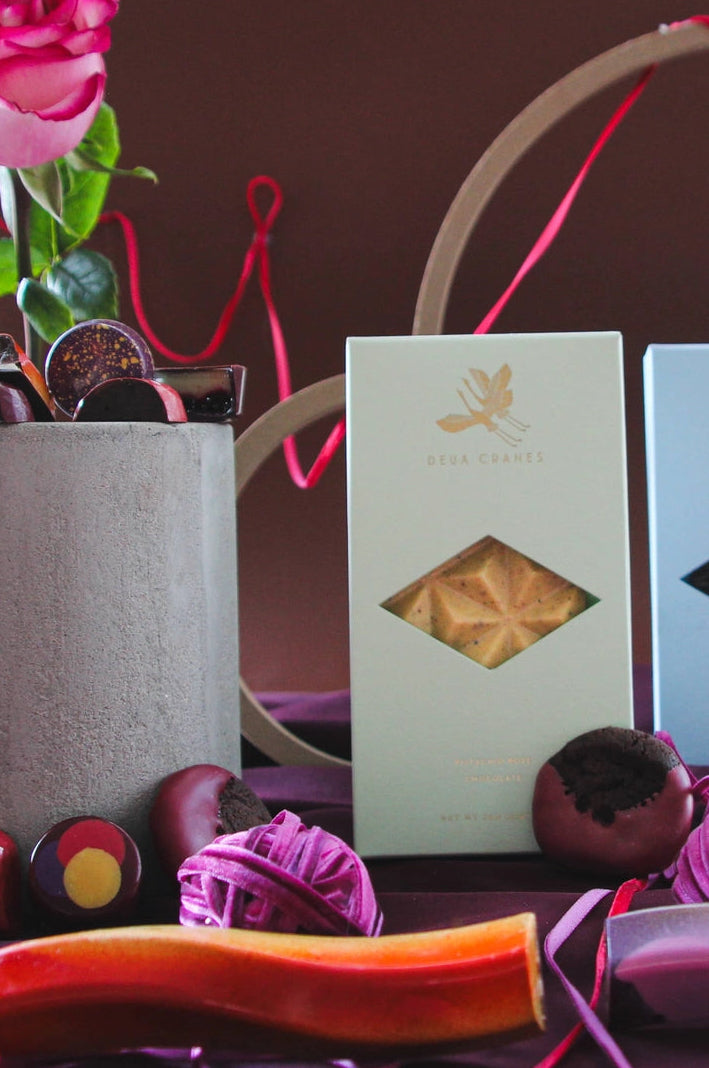 Two boxes of chocolate with decorative ribbons and flowers on a dark background ©Deux Cranes