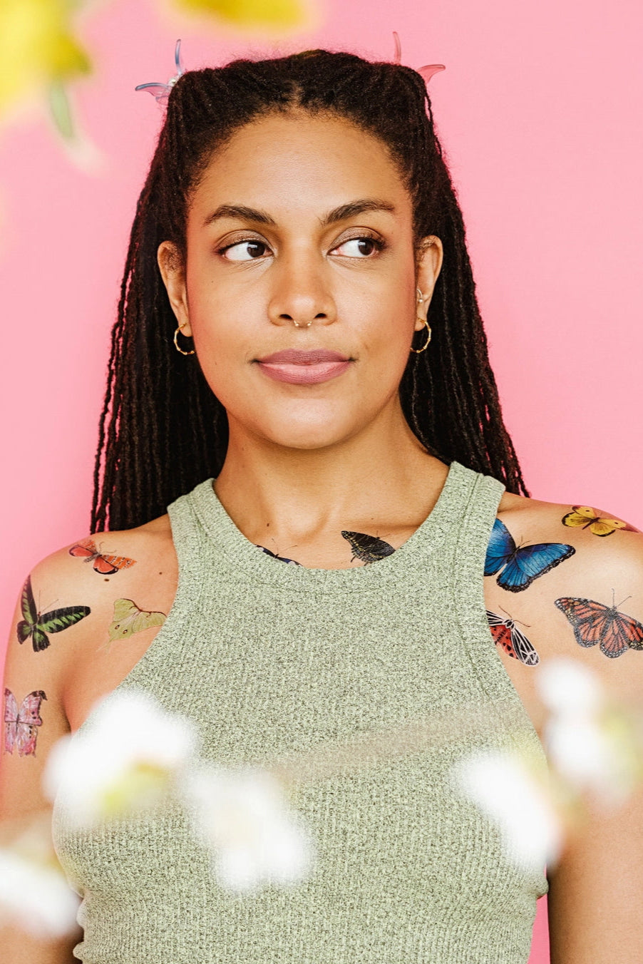 Woman with butterfly tattoos from Tiny Butterfly Tattoo Tin on a pink background ©Tattly