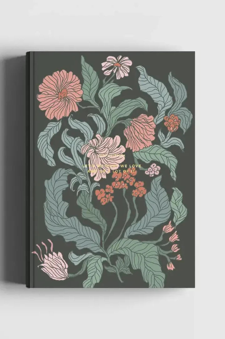 The Floral Desert Rose Notebook with its pink flowers, green leaves on a dark background.