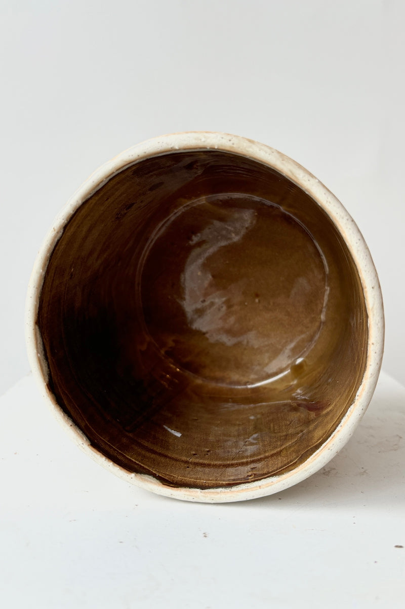 Interior of stoneware cachepot with brown, glazed interior. Does not contain drainage holes.