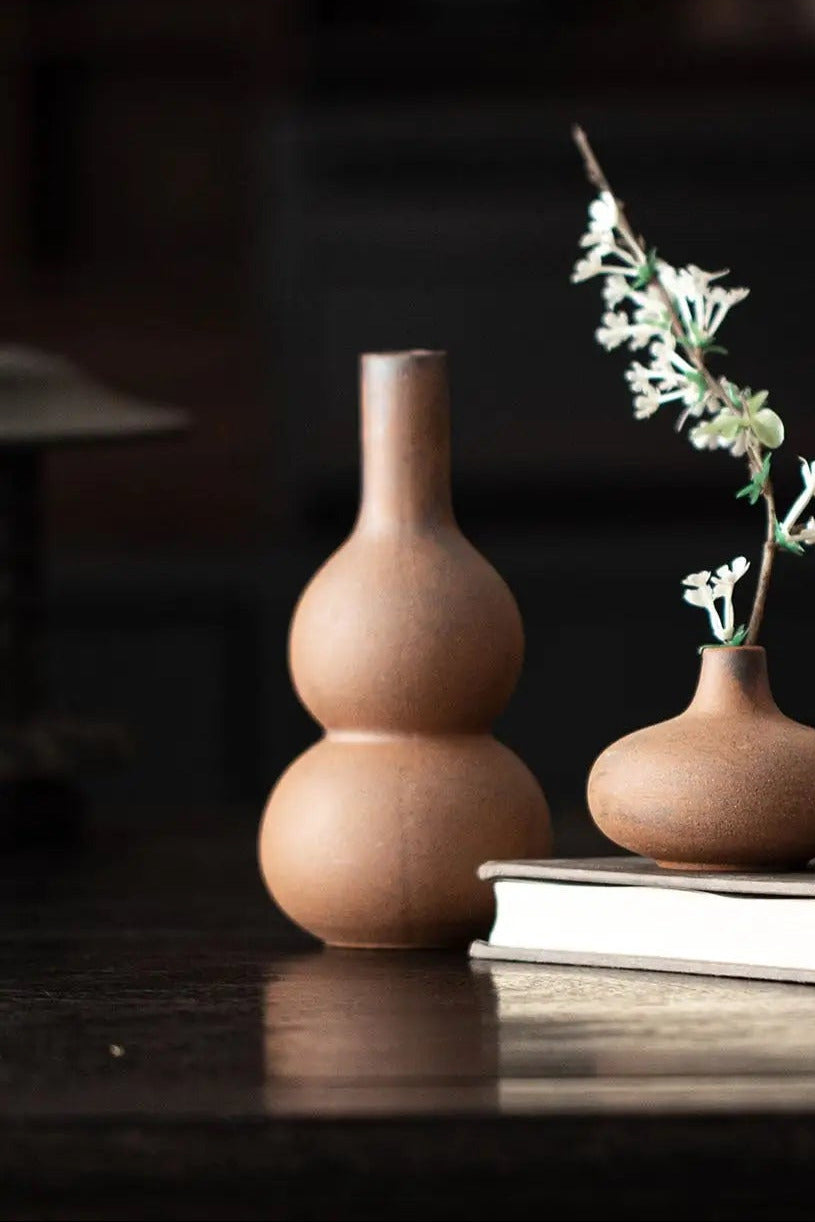 unglazed gourd vase on a dark surface with a blurred background ©Haku