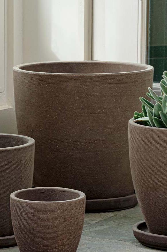 Carob terra cotta Lara Planter Extra large empty and surrounded by other sizes of Lara planters in Carob. 