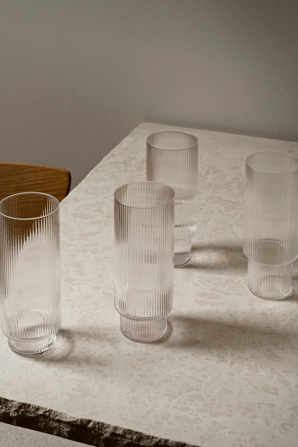 Set of 4 tall clear ripple glasses sitting on a stone counter in a style shot.